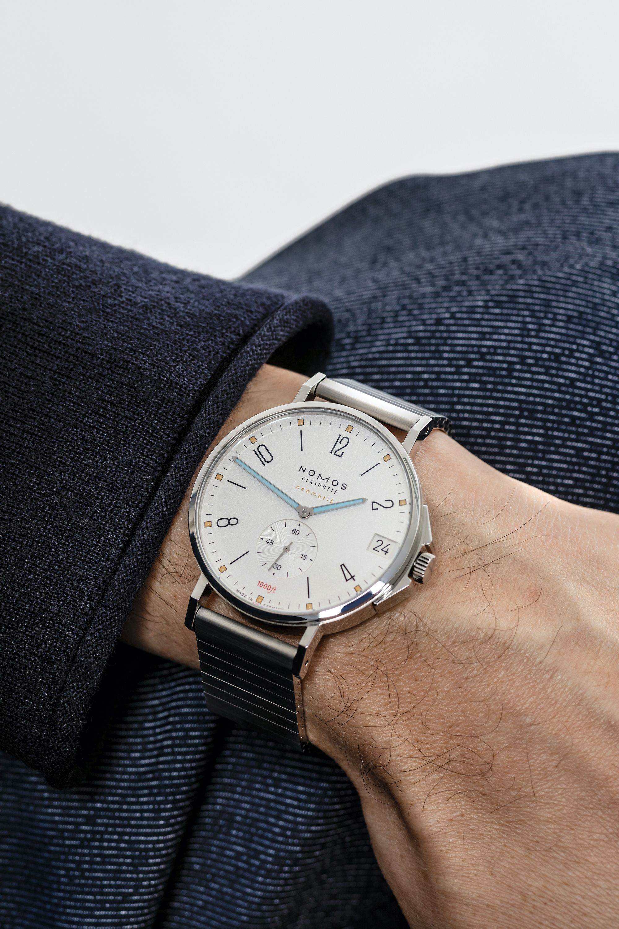 Wrist wearing a Nomos watch with a blurred background