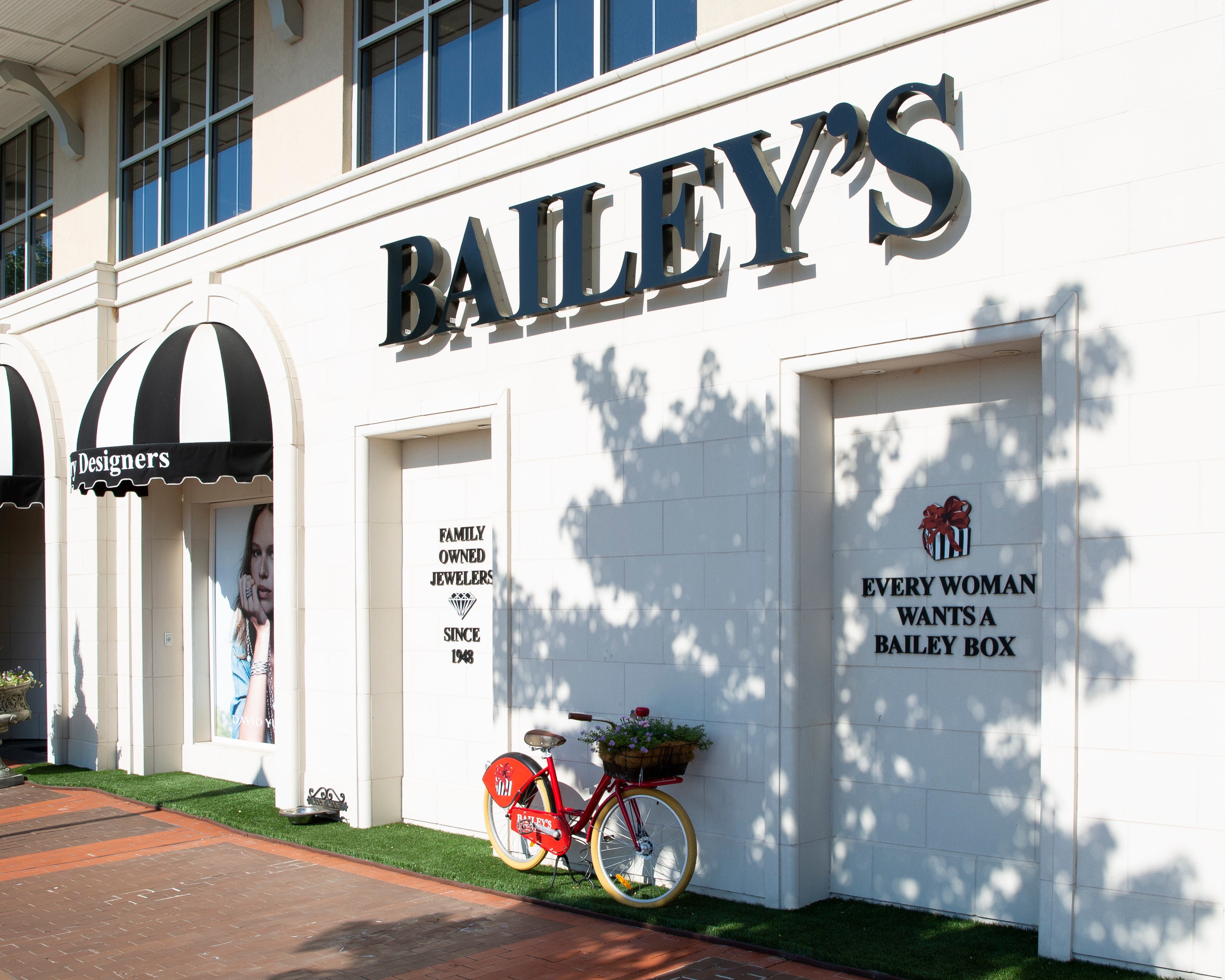Bailey's jewelry store with a bicycle and promotional sign on a white building.