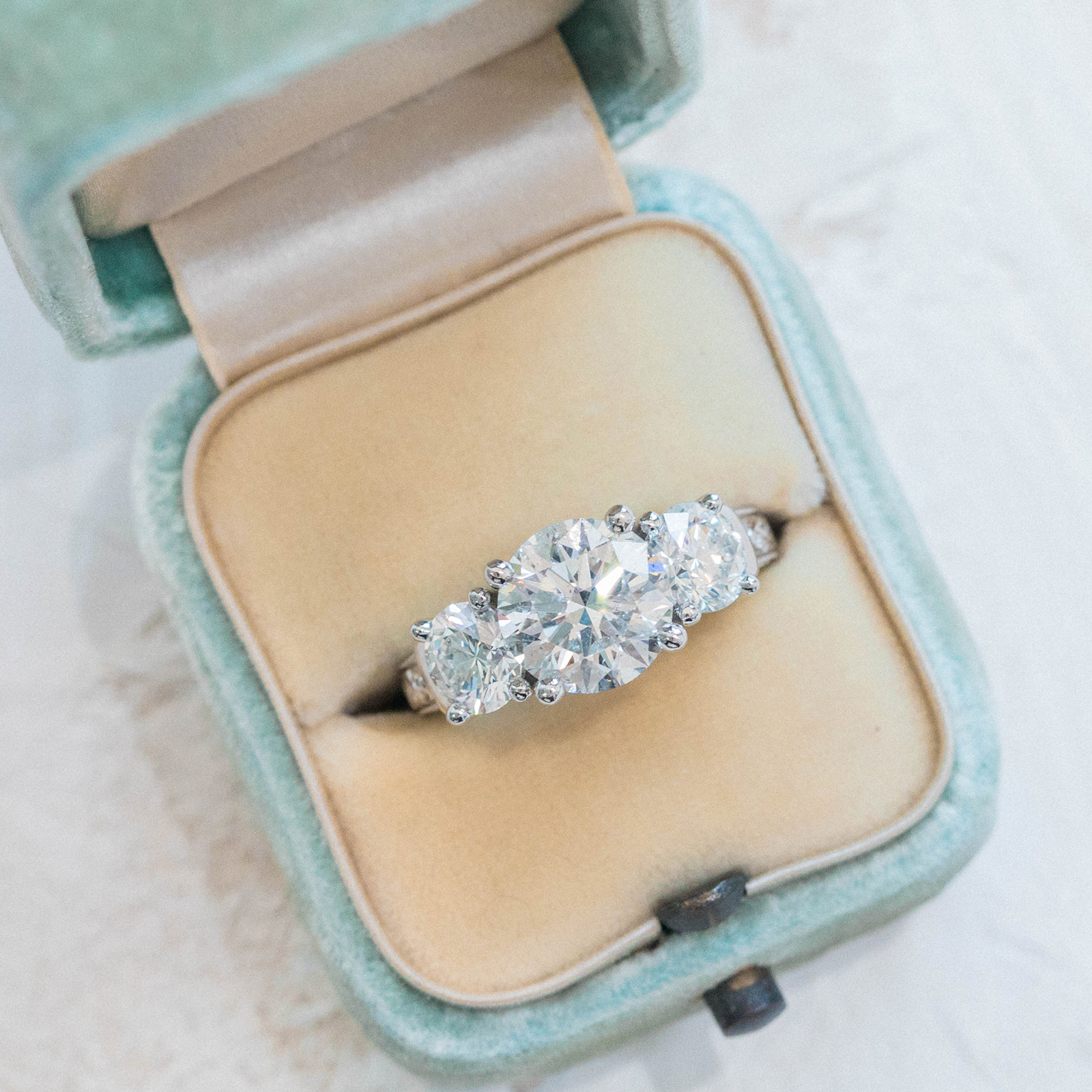 Diamond ring in a light blue velvet box on a white background
