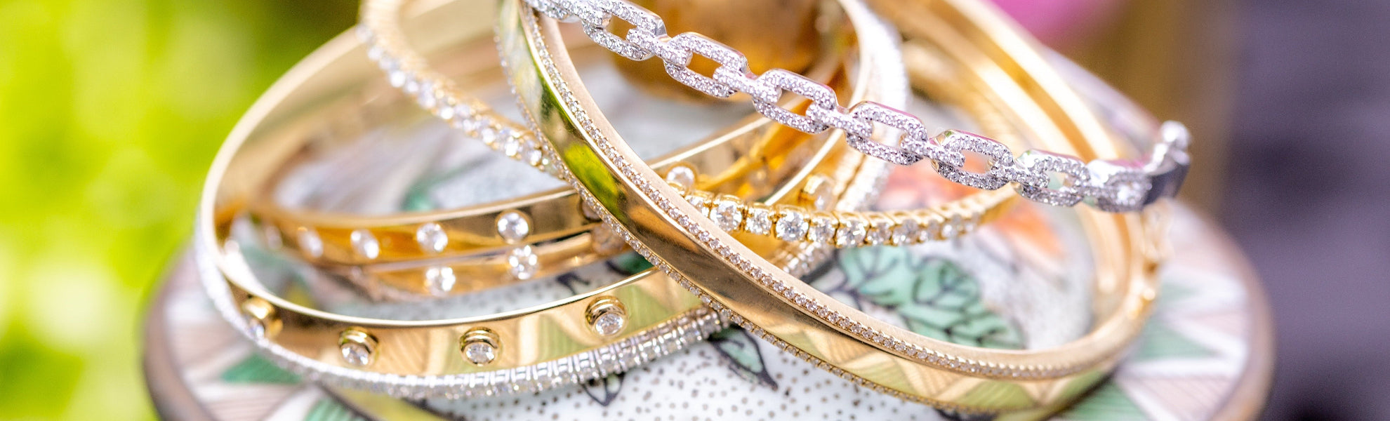 Stack of gold and silver rings on a decorative plate with a blurred green background