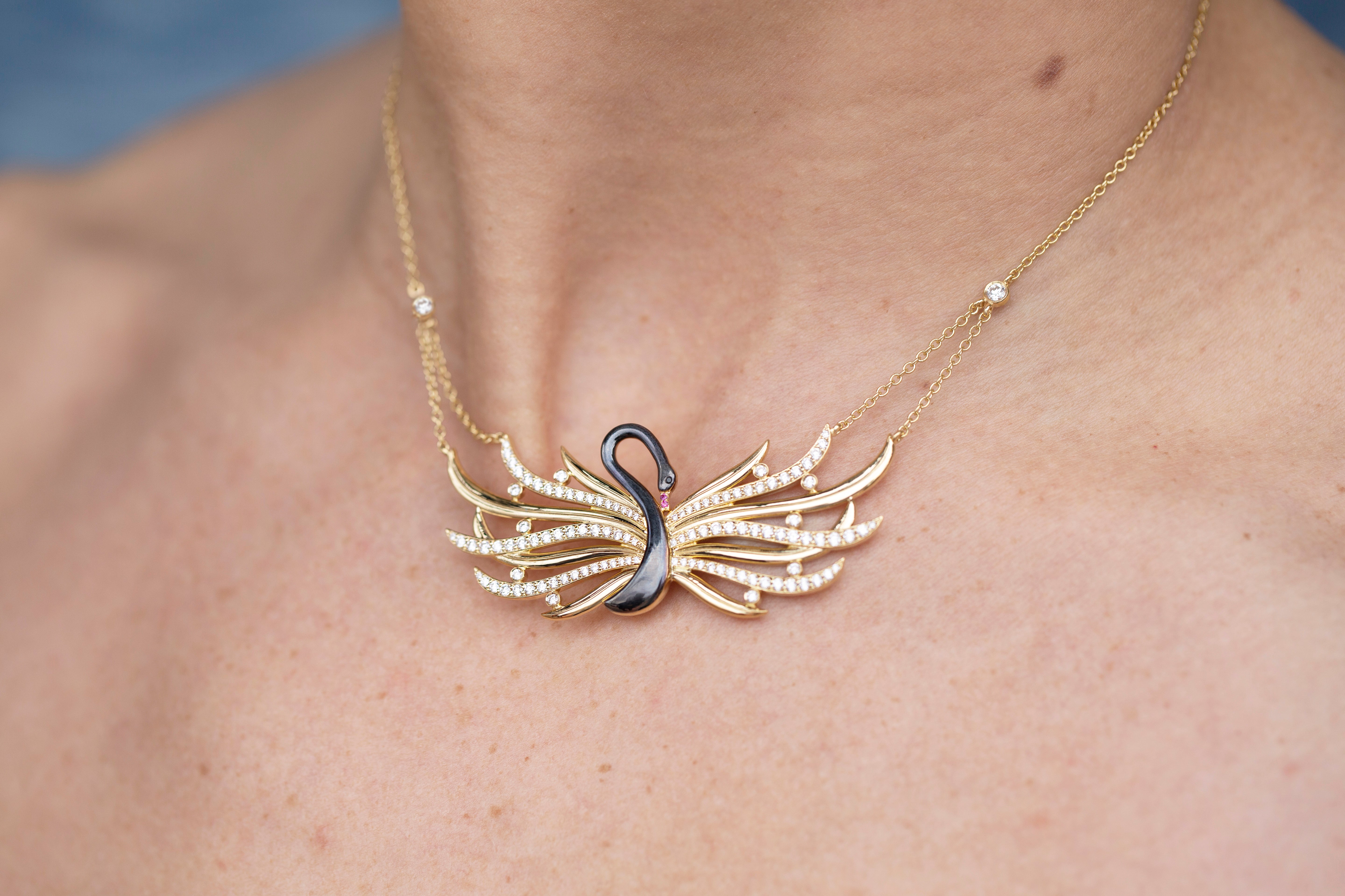 Gold necklace with a unique black swan pendant on a person's neck against a blue background