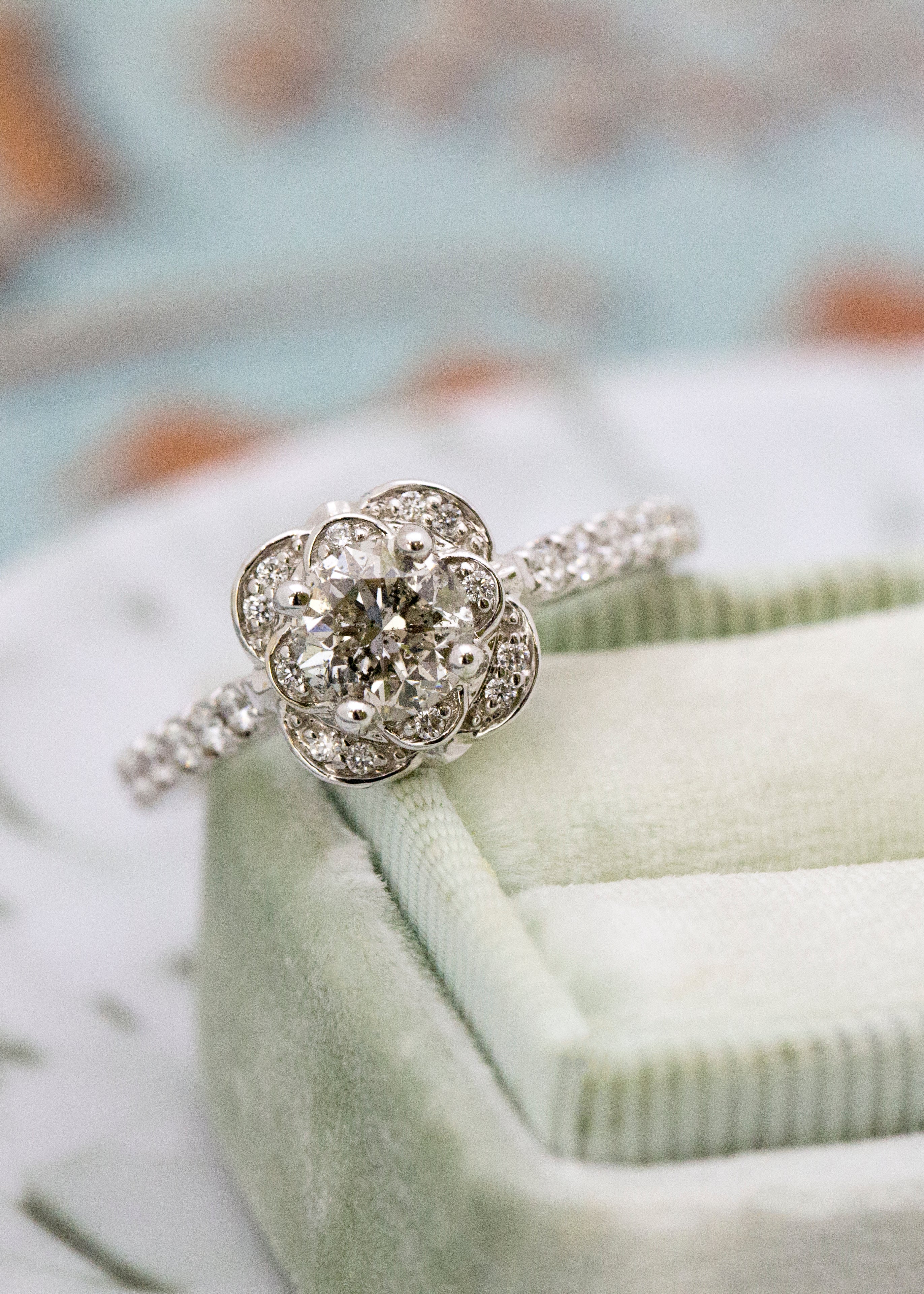 Silver ring with diamonds on a light green cushion