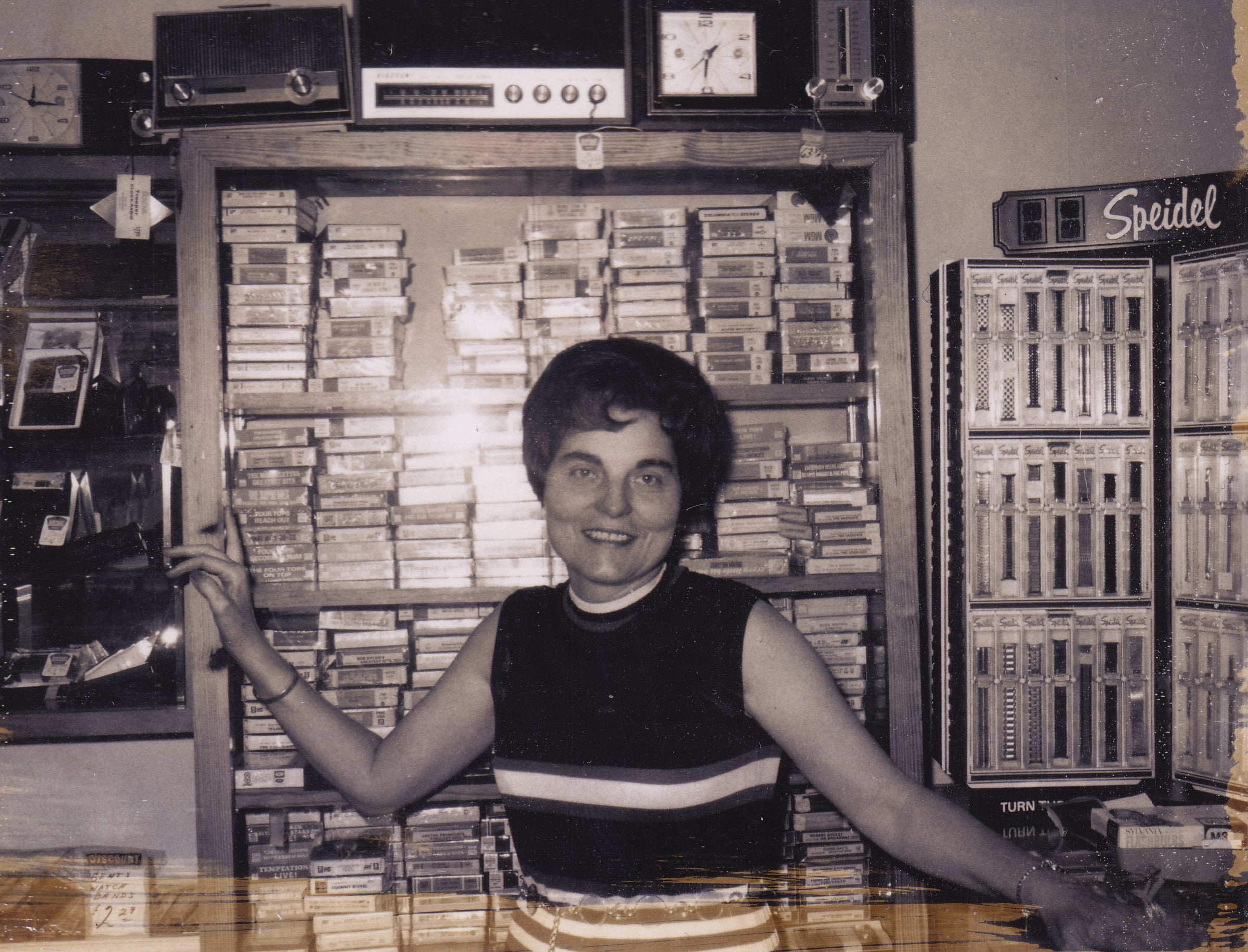 Person standing in front of a large collection of tapes or records in a store.