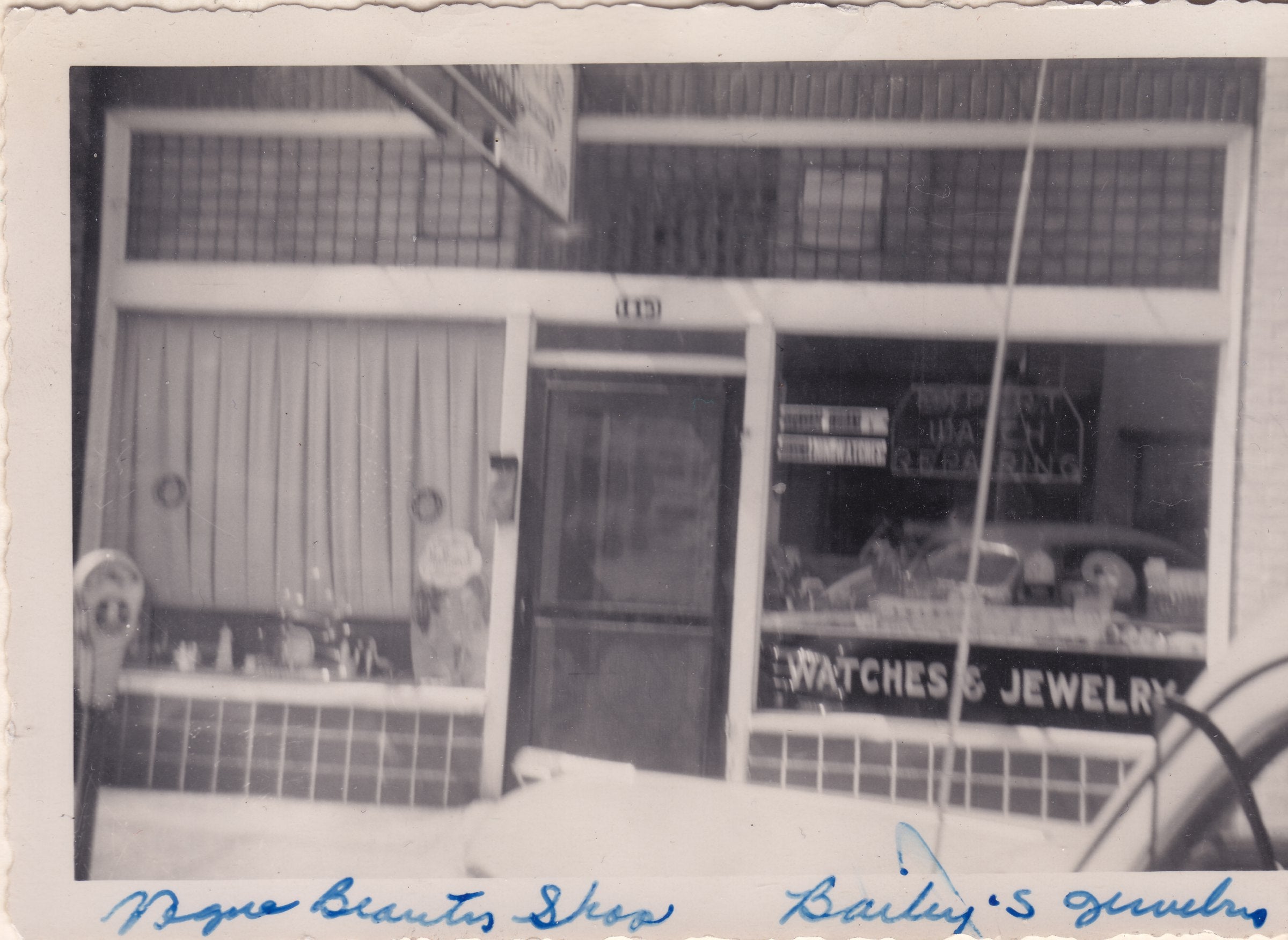 Vintage black and white photo of a store front with 'Watches & Jewelry' sign.