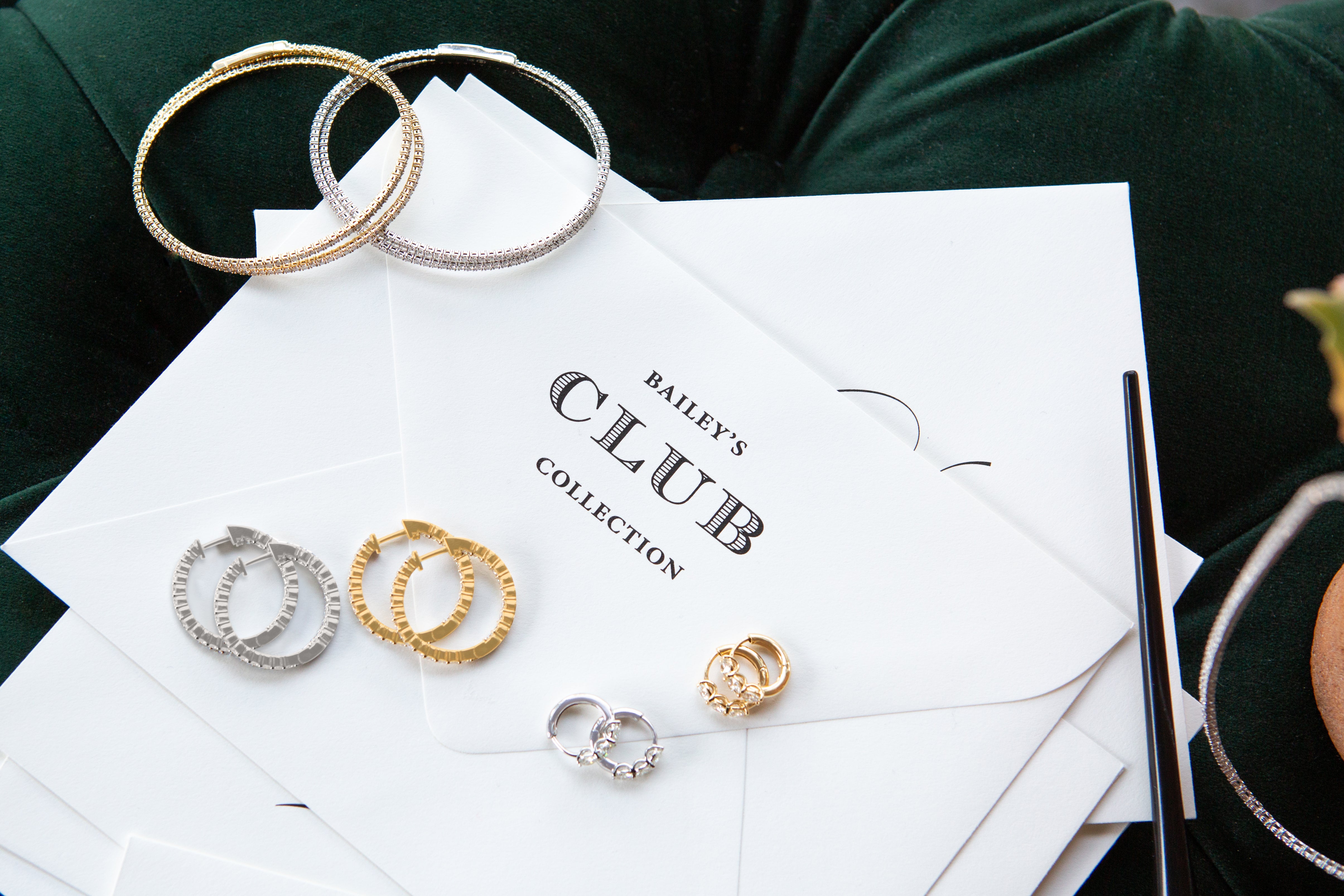 Gold and silver hoop earrings on a 'Bailey's Club Collection' card with a green fabric background.