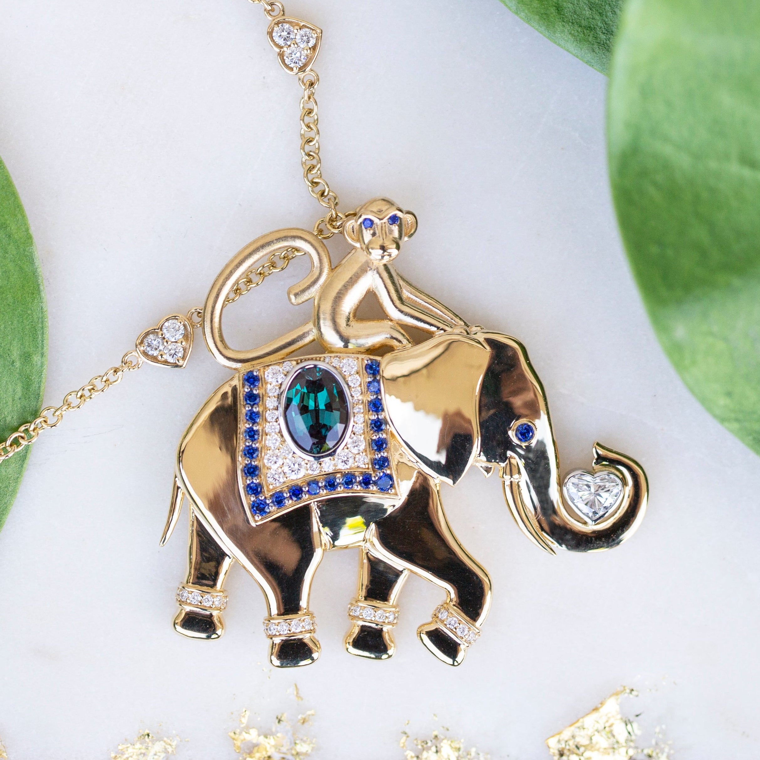 Gold elephant pendant with gemstones on a white background