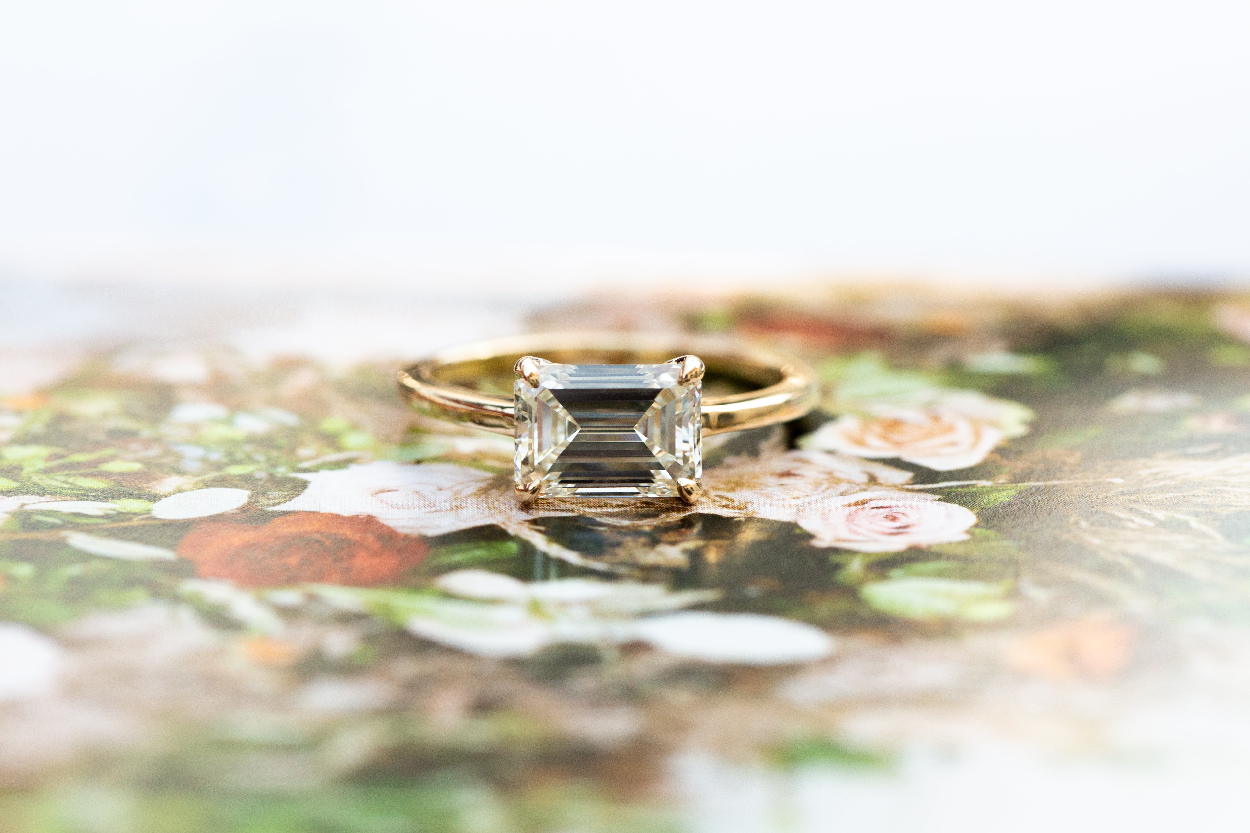 Gold ring with a green gemstone on a floral background