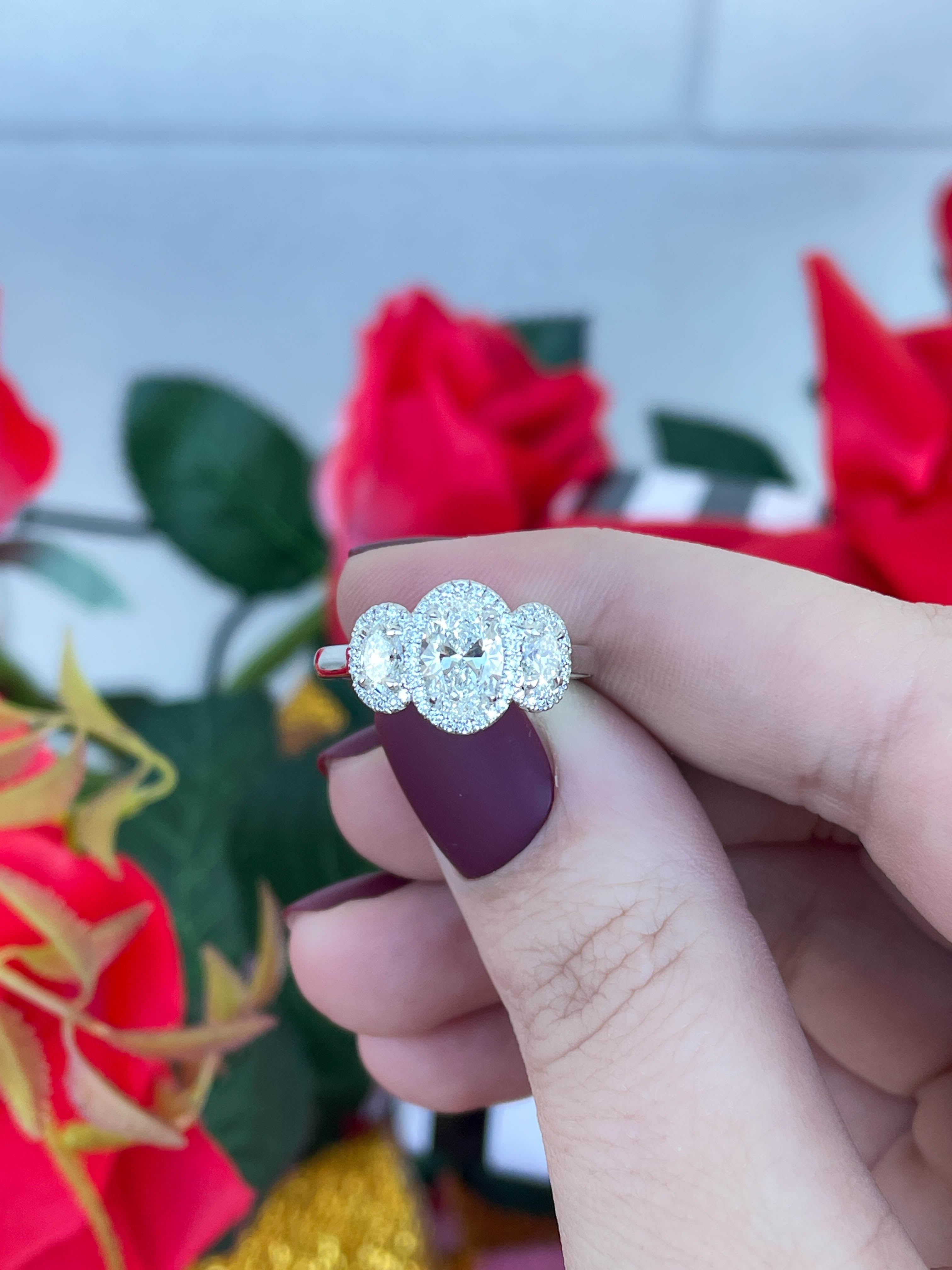 Silver ring with a diamond design held by a hand against a floral background
