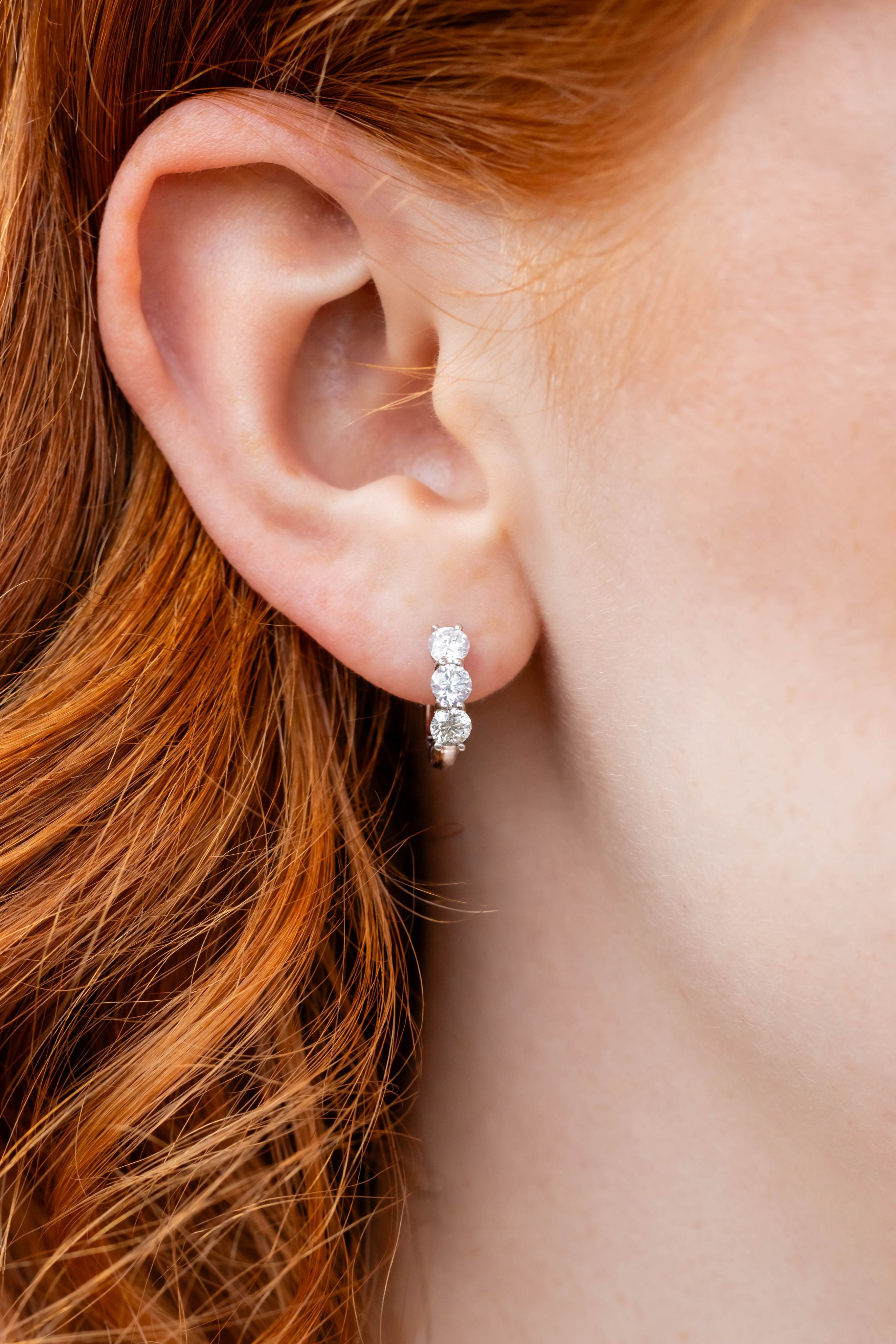 Close-up of an ear wearing a silver earring with red hair.