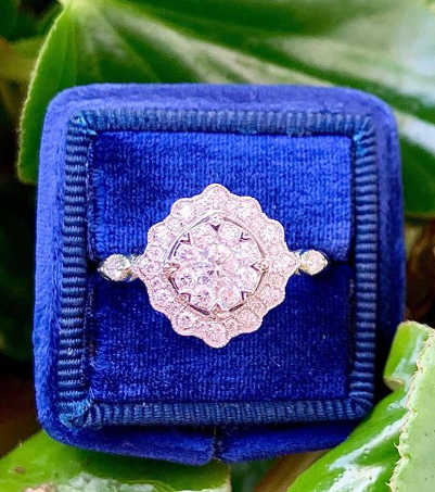 unique diamond ring in blue square fabric box on green leaf background