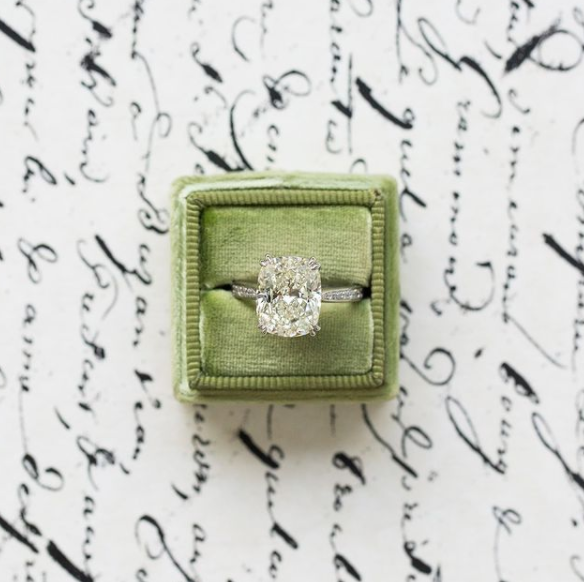 Diamond ring in a green velvet box on a white background with black text