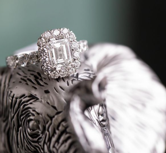 large diamond ring on a sculpted silver surface and blurred green background