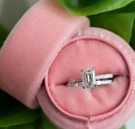 Diamond ring in a pink jewelry box with green leaves in the background