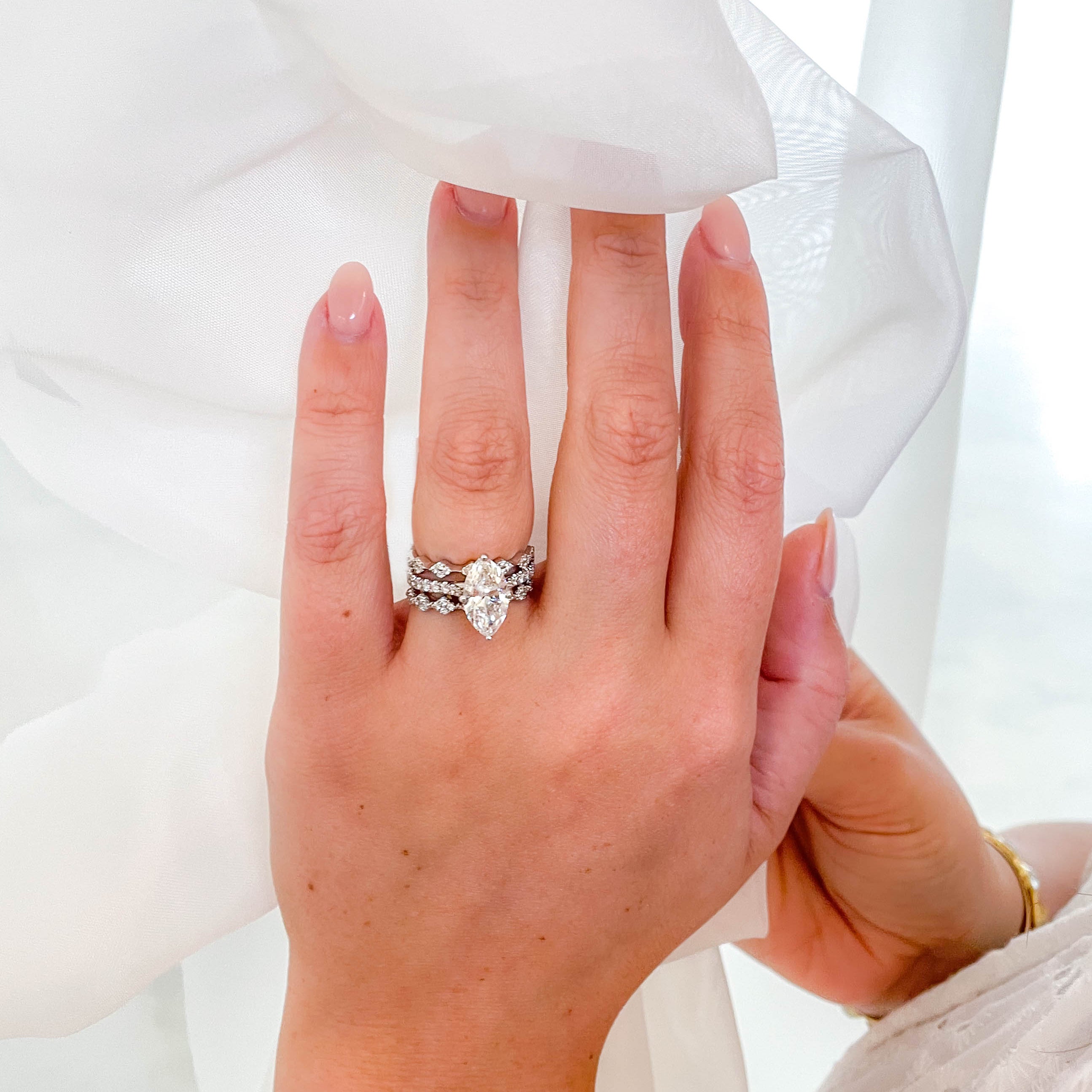 Hand wearing a diamond ring with a white background