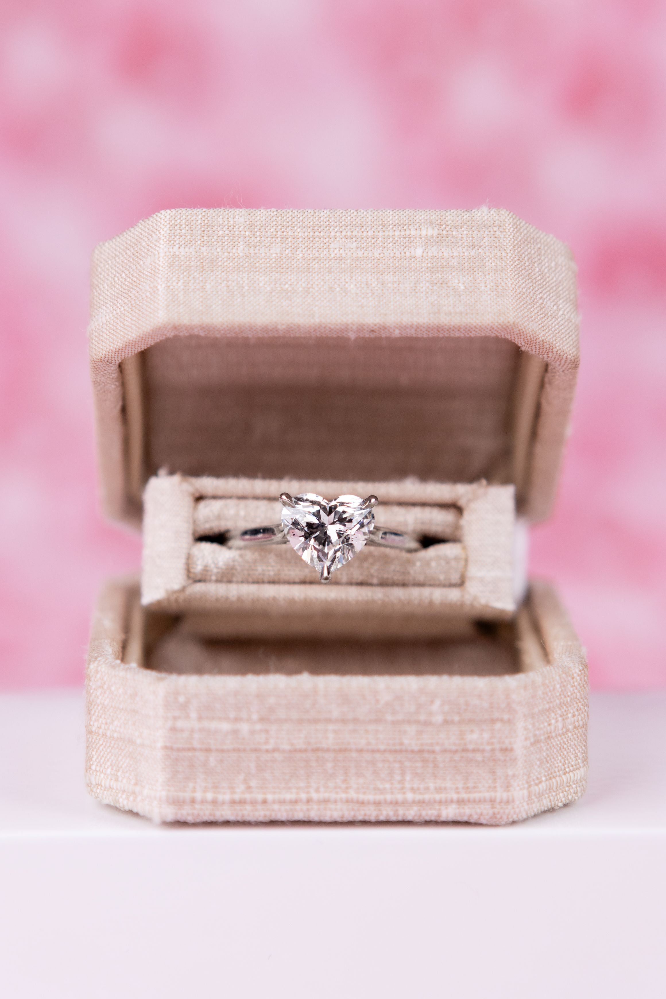 heart-shaped diamond in a pink box with a blurred pink background