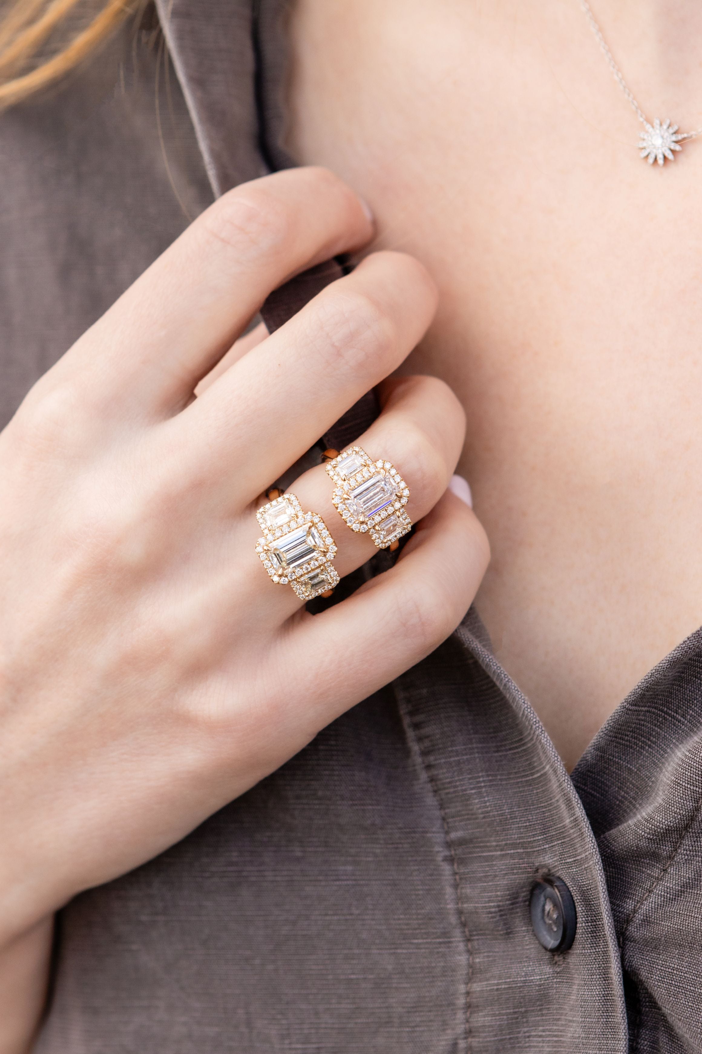 hand wearing two diamond rings with brown and neutral background