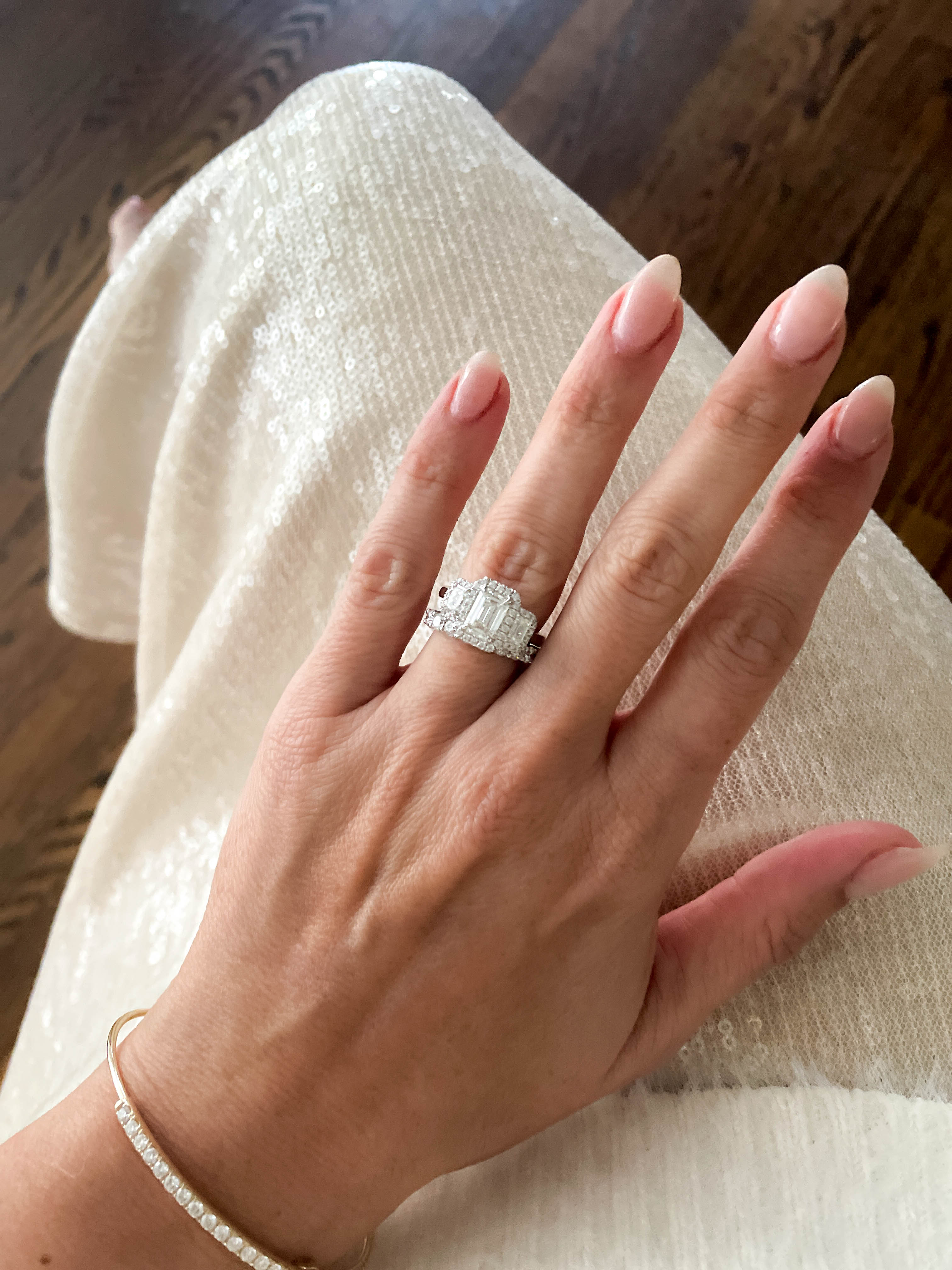 Hand wearing a diamond ring on a wooden floor background
