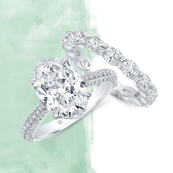 Silver ring with a large diamond and smaller diamonds on a light green background