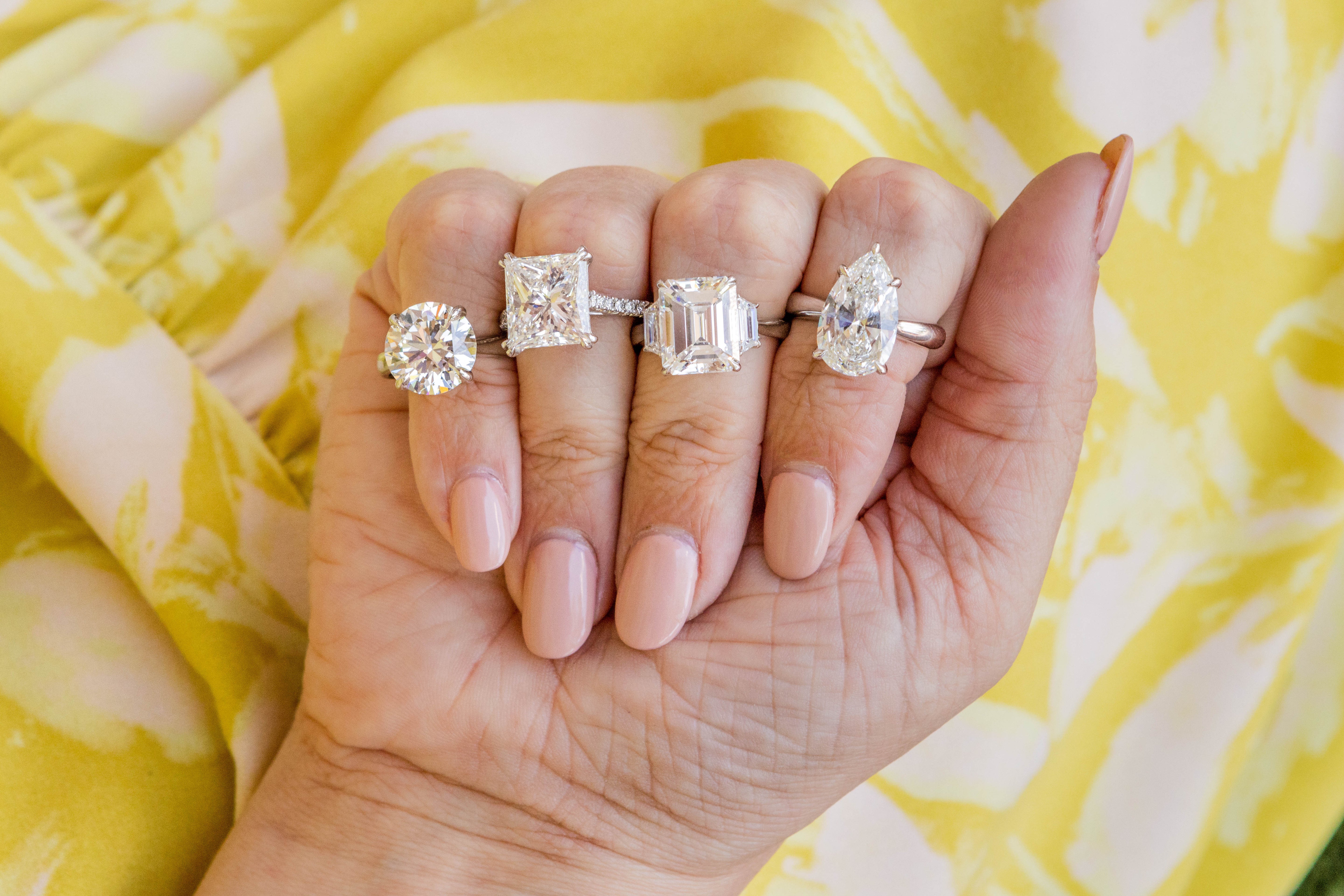 Hand wearing four diamond rings on a yellow patterned background