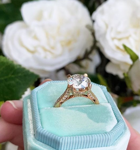 Diamond ring in a light blue velvet box with white flowers in the background