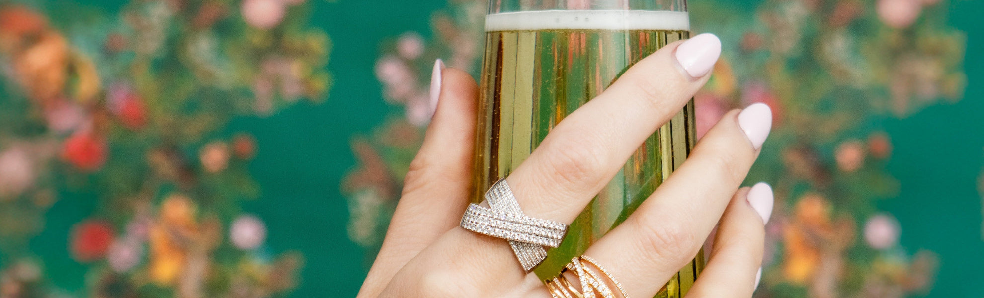 Hand holding a glass of champagne with floral background