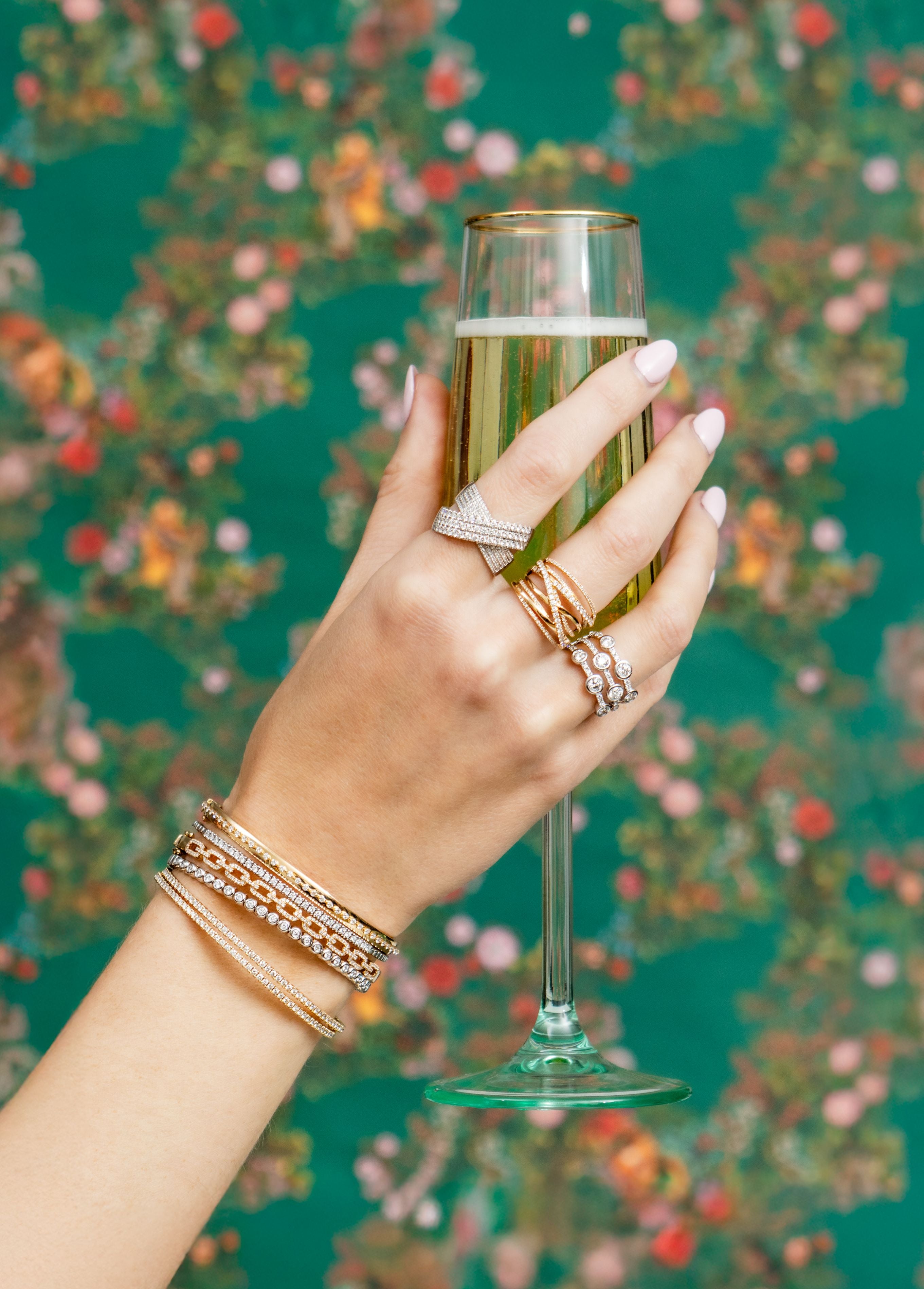 Hand holding a glass of champagne with a floral background