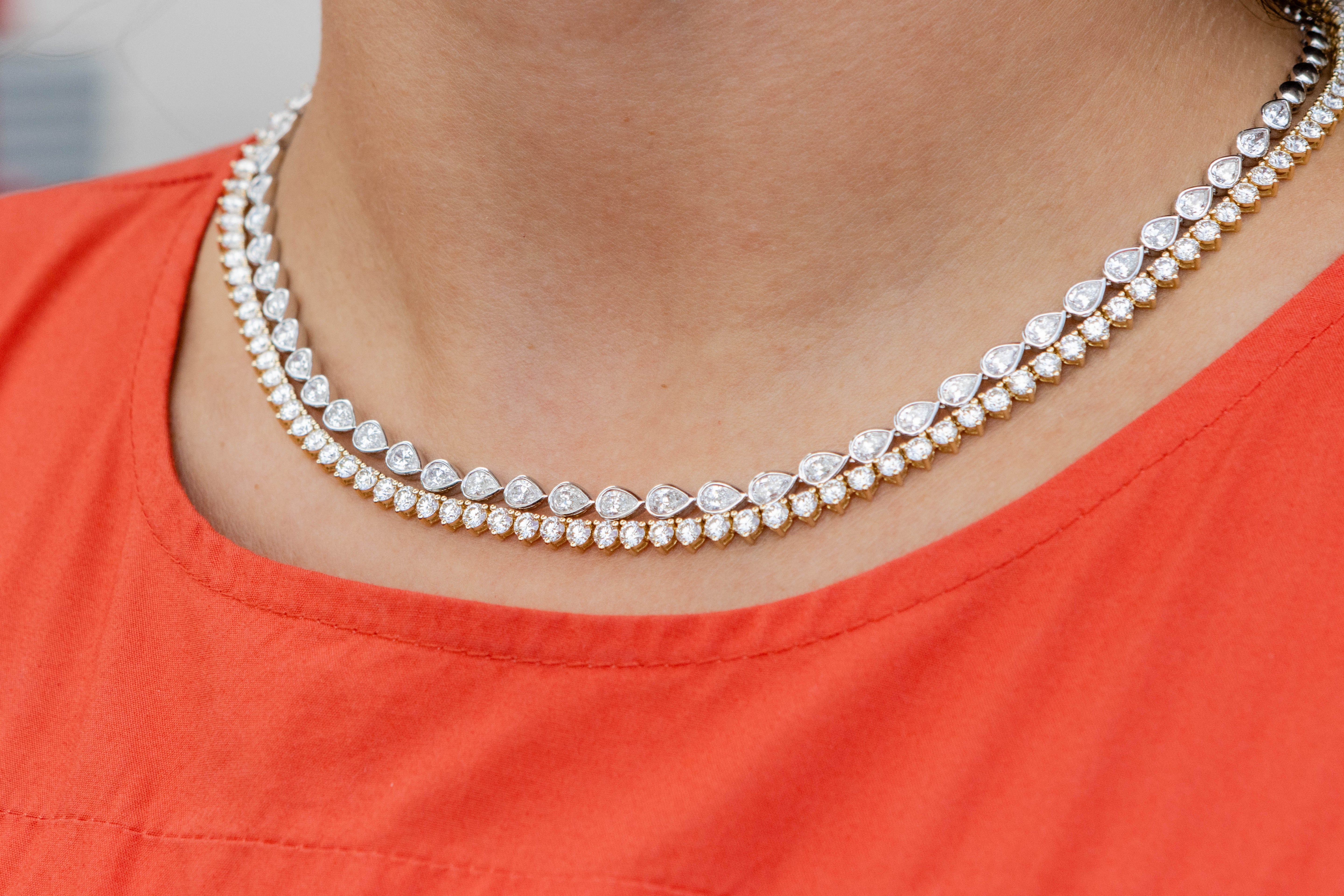 Close-up of a person wearing layered diamond necklaces on an orange top.