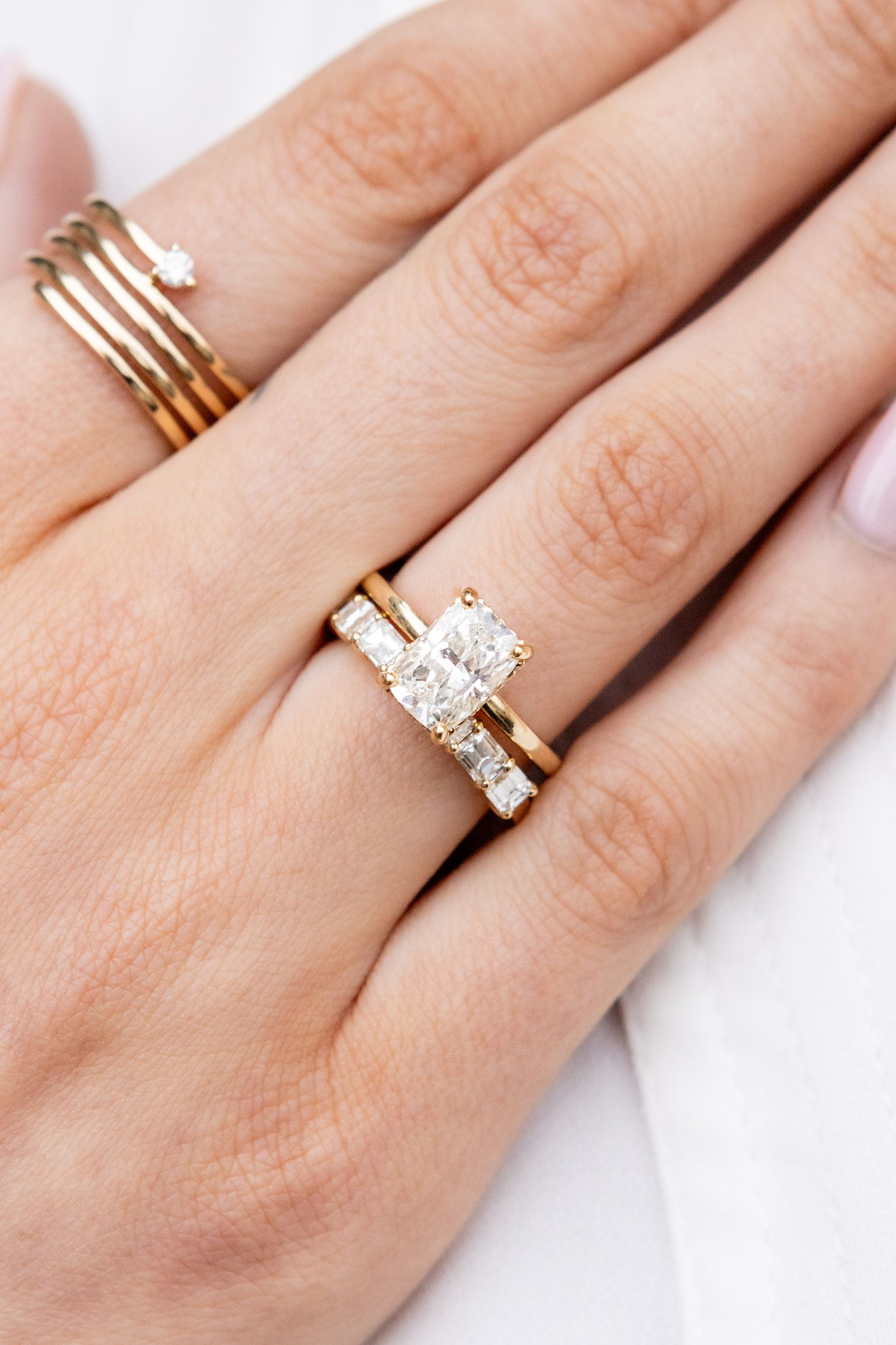Close-up of a hand wearing a gold ring with a diamond on a white background