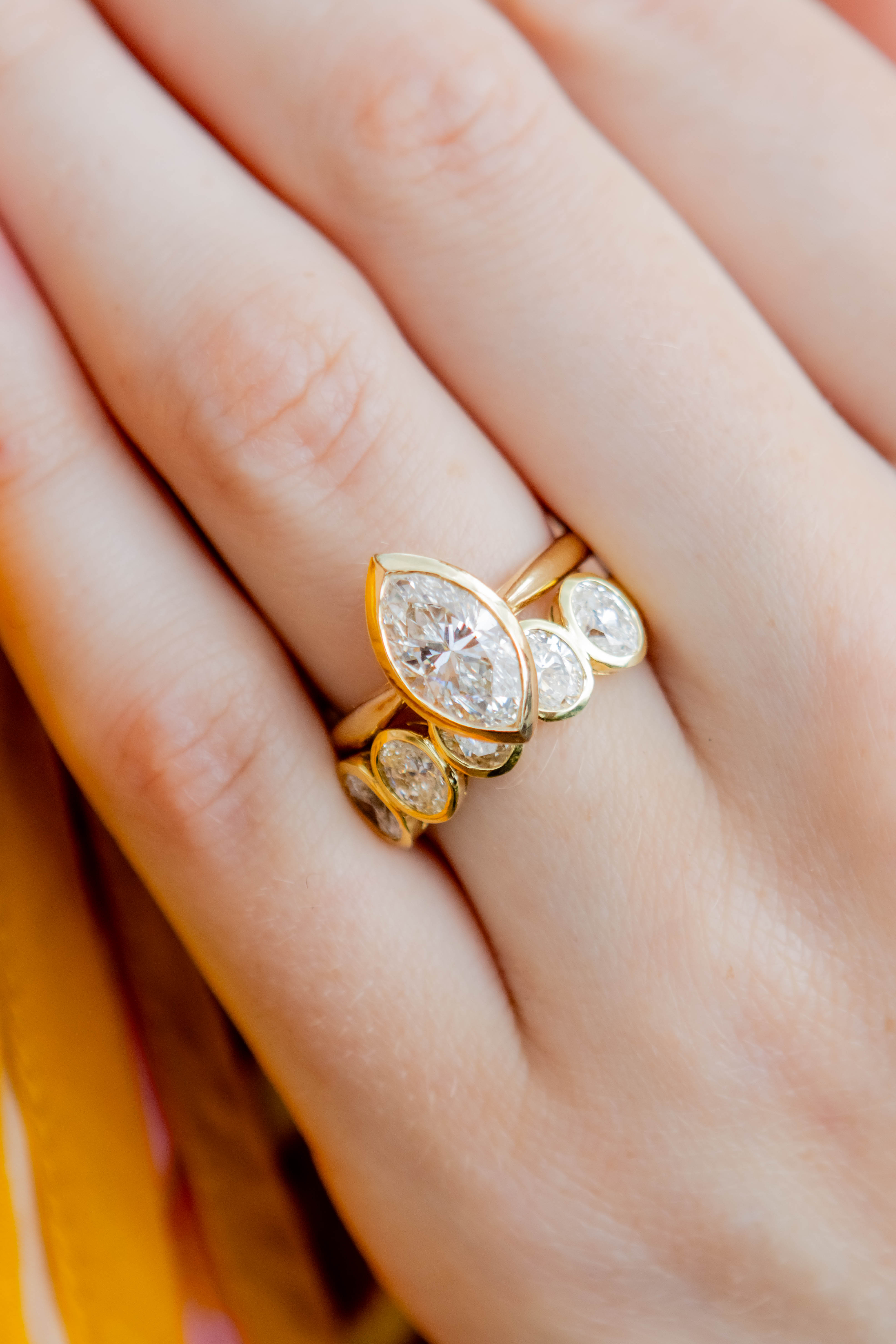 gold diamond rings on a hand against an orange background