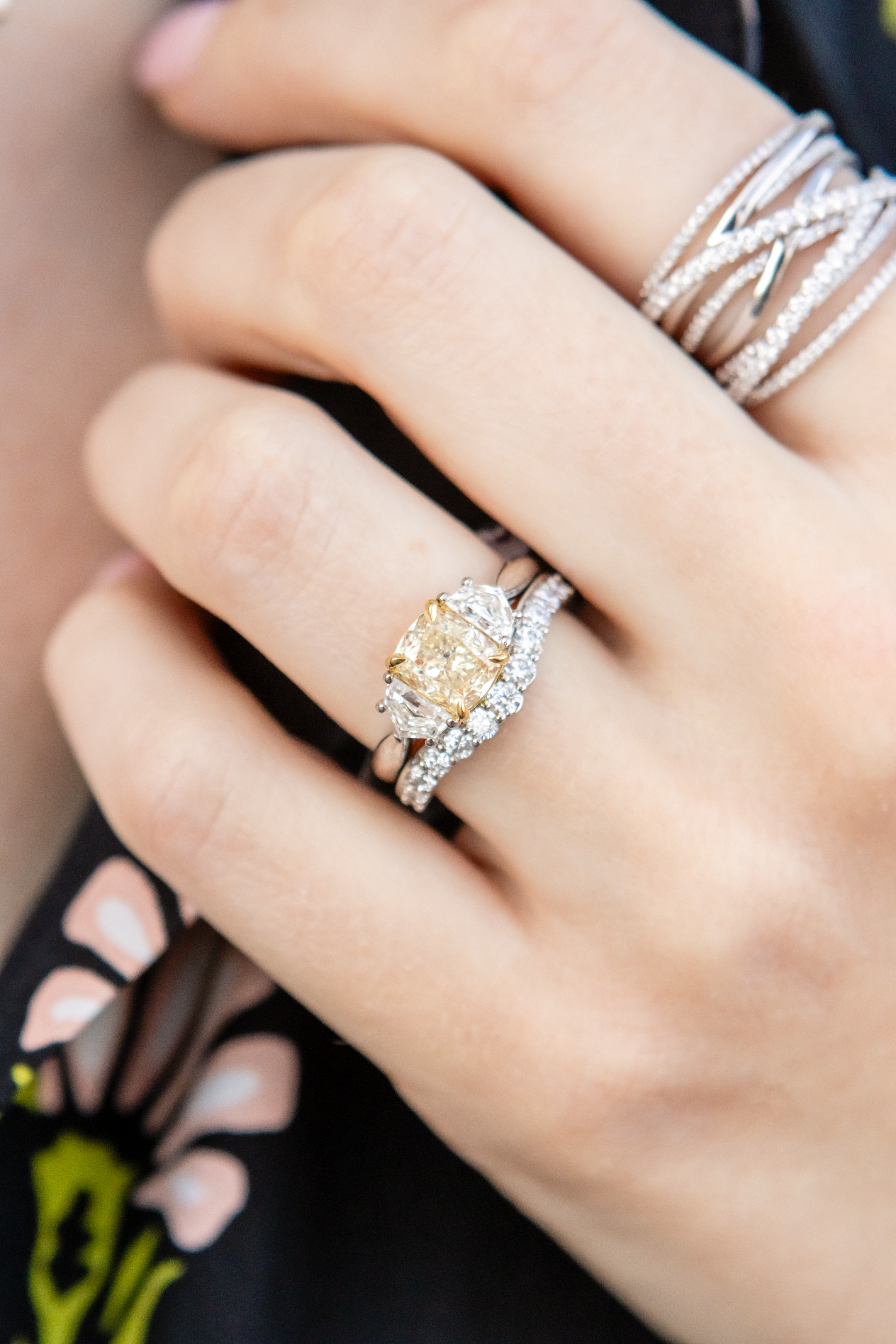 close-up of diamond rings on a hand against a black floral background