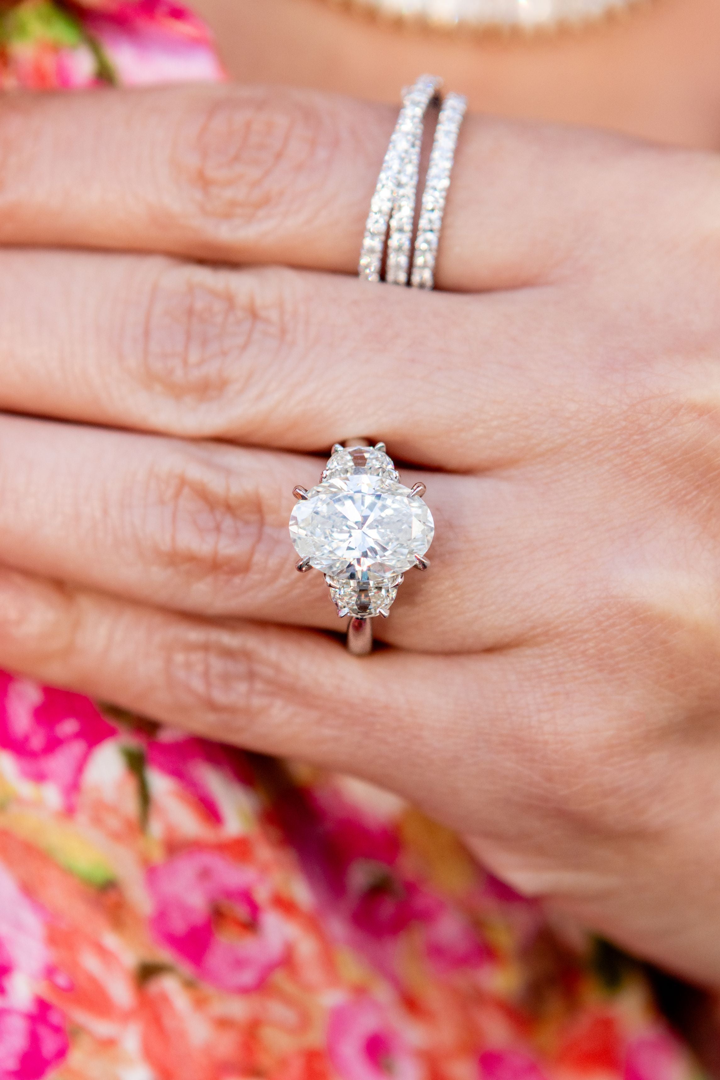 Close-up of a hand wearing a diamond ring with a floral background