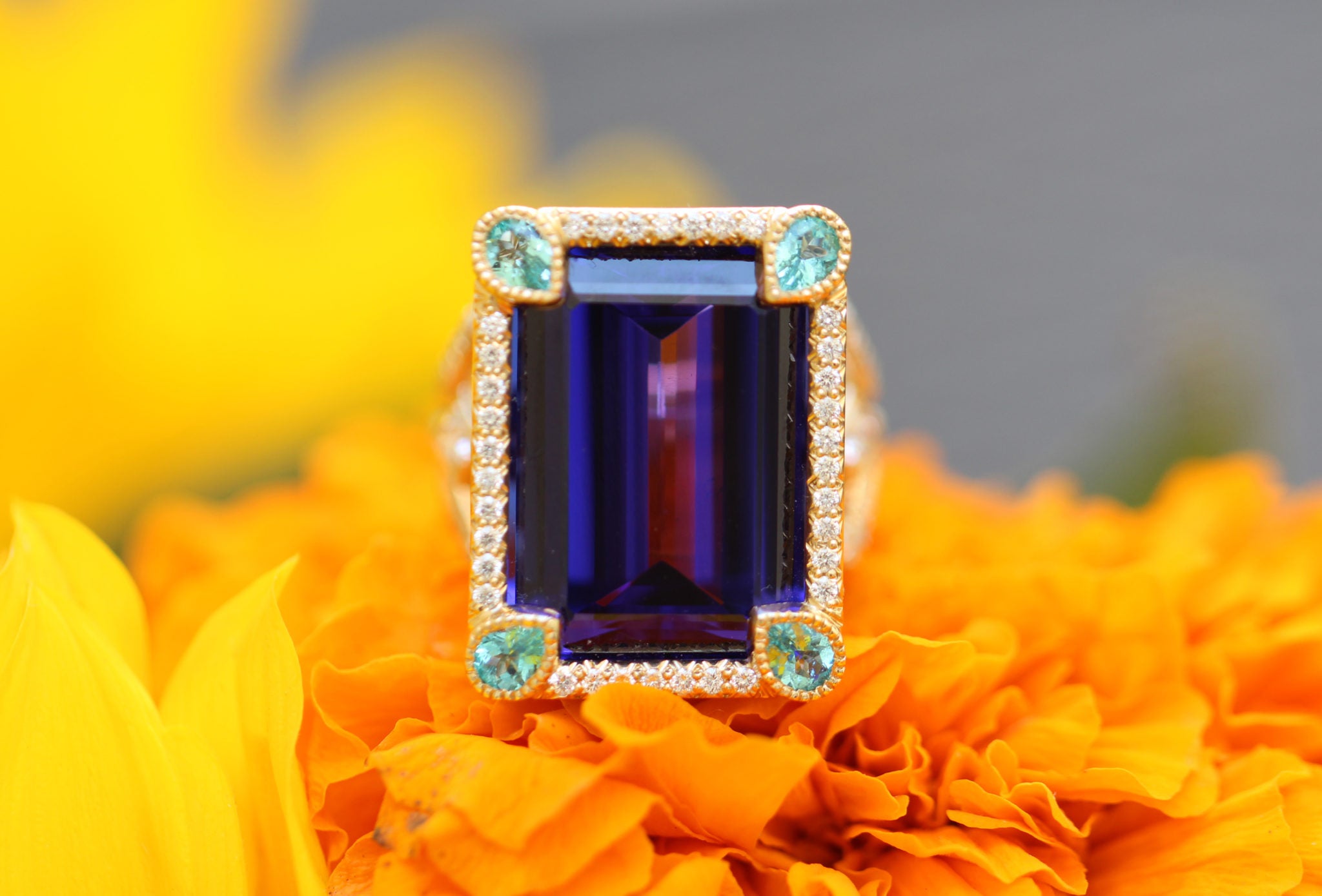 Ring with a purple gemstone and gold accents on orange flowers