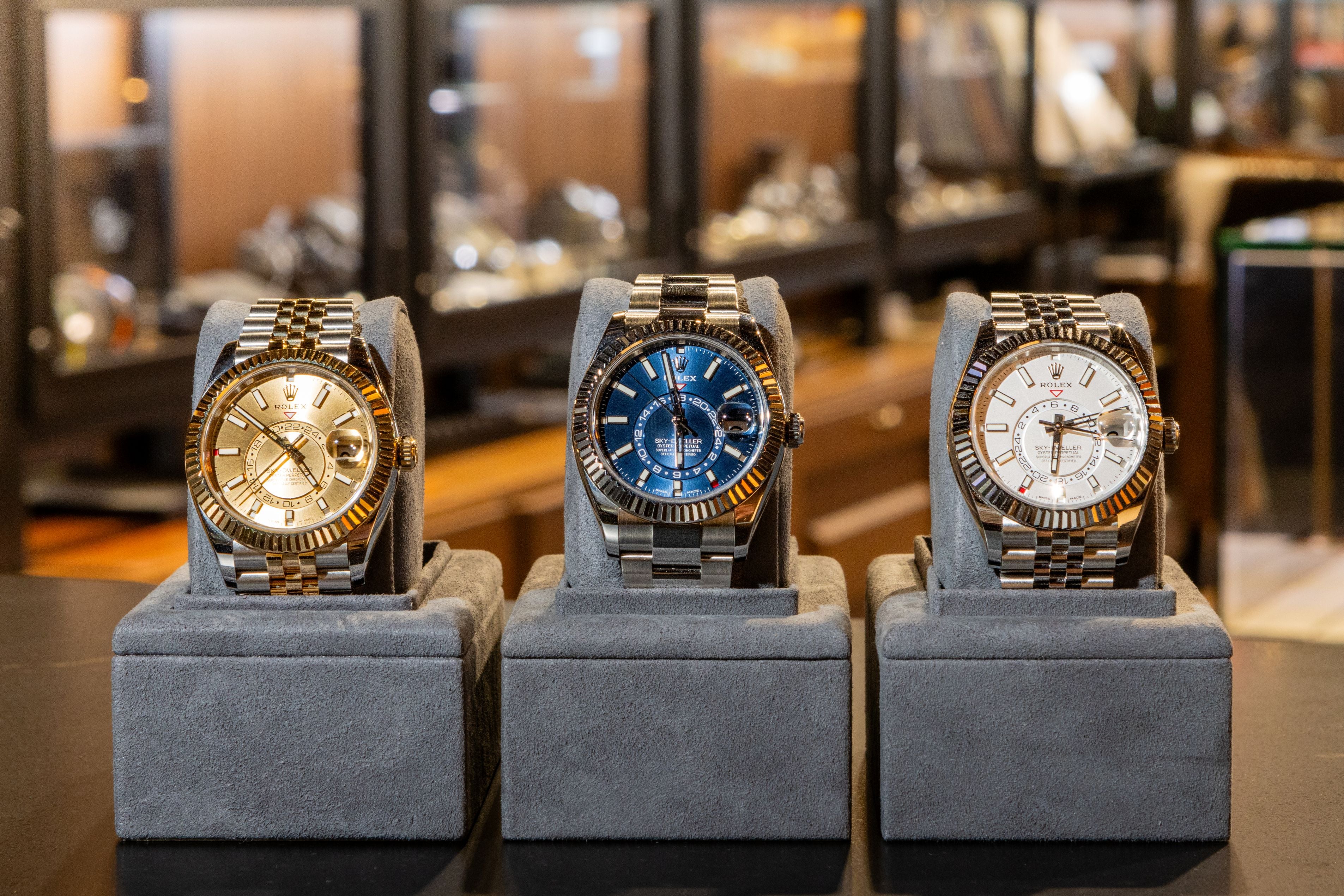 Three gold wristwatches on gray stands in a store setting