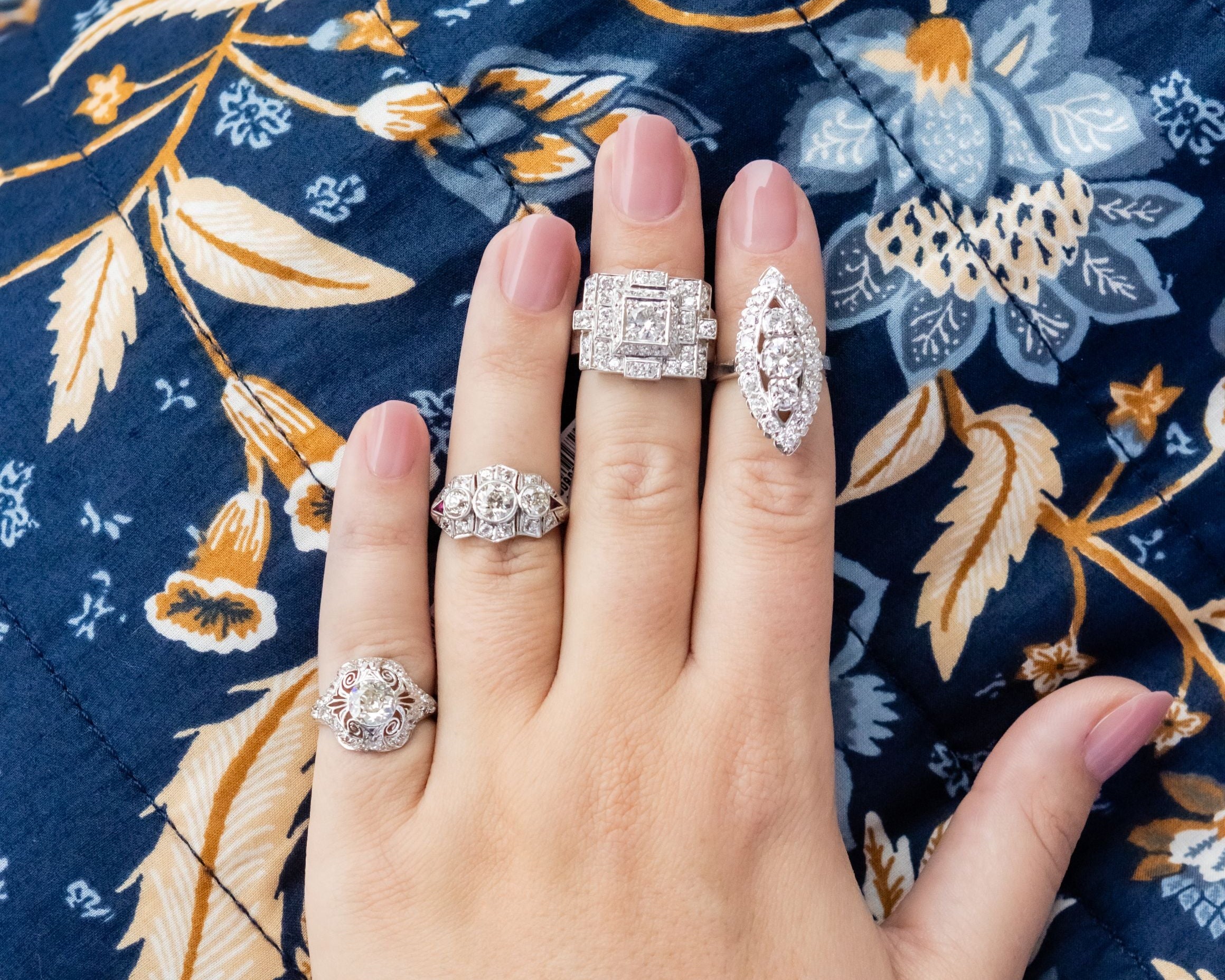 Hand wearing multiple rings with a floral patterned fabric background
