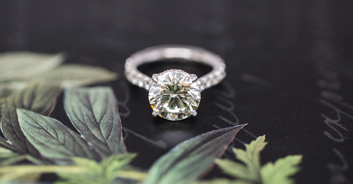 Diamond ring on a dark surface with green leaves