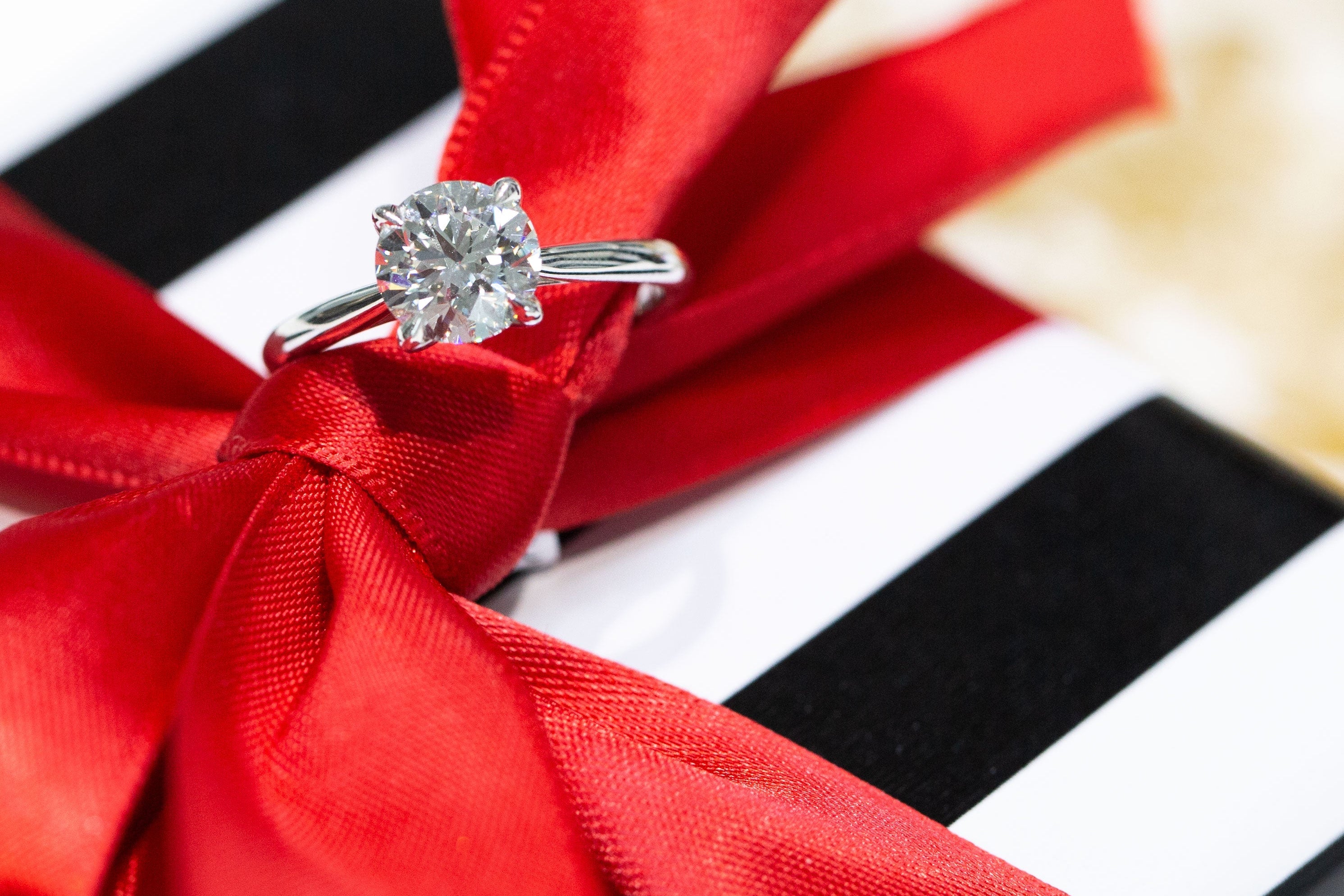 Diamond ring on a red ribbon with a black and white striped background