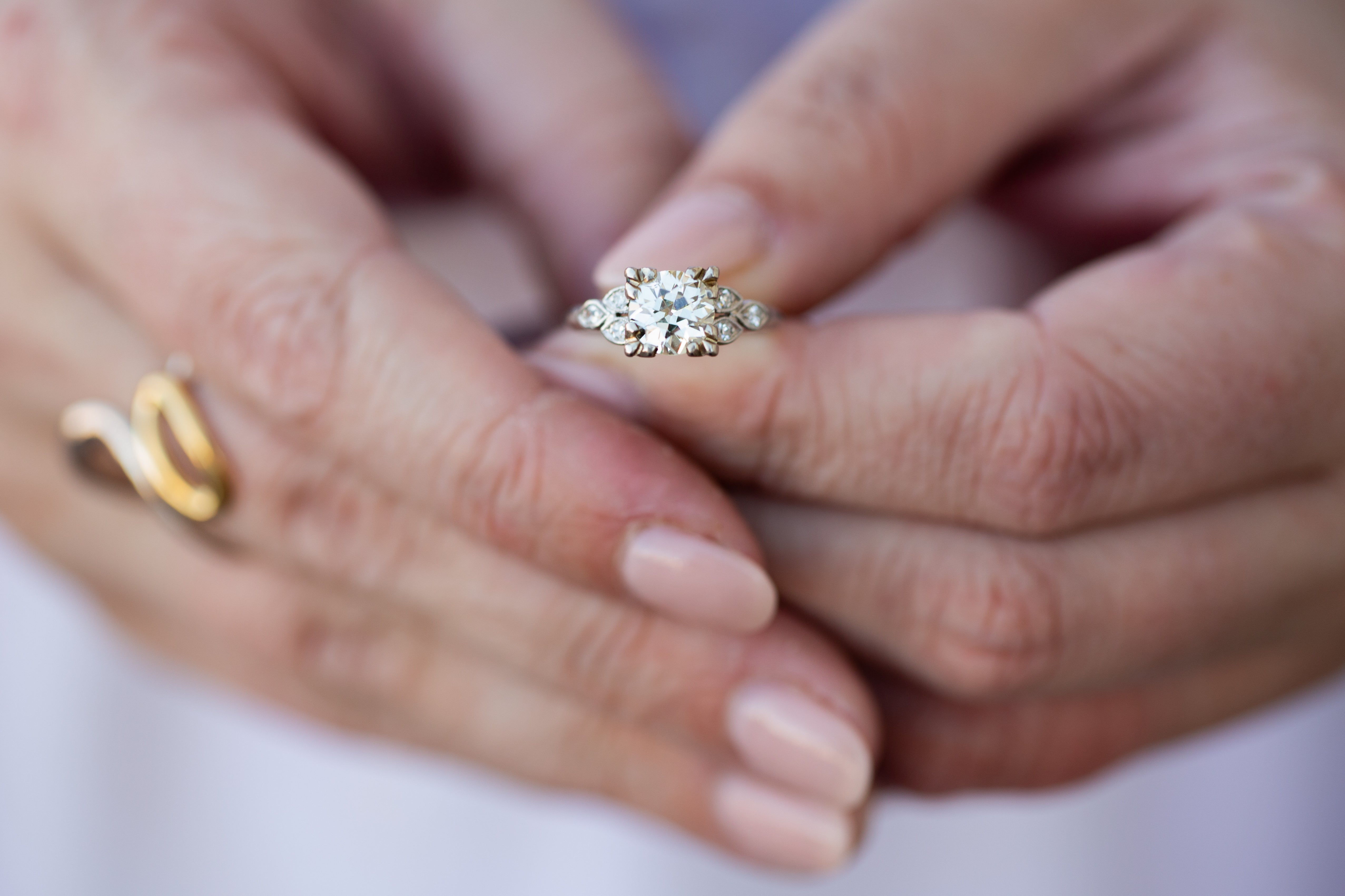 Close-up of hands with a silver diamond ring on a white background