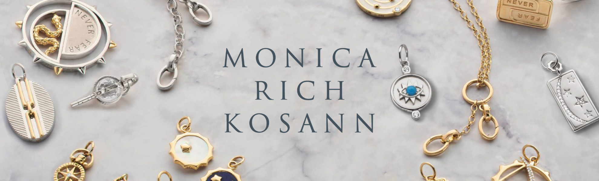 Jewelry collection with 'Monica Rich Kosann' branding on a marble background