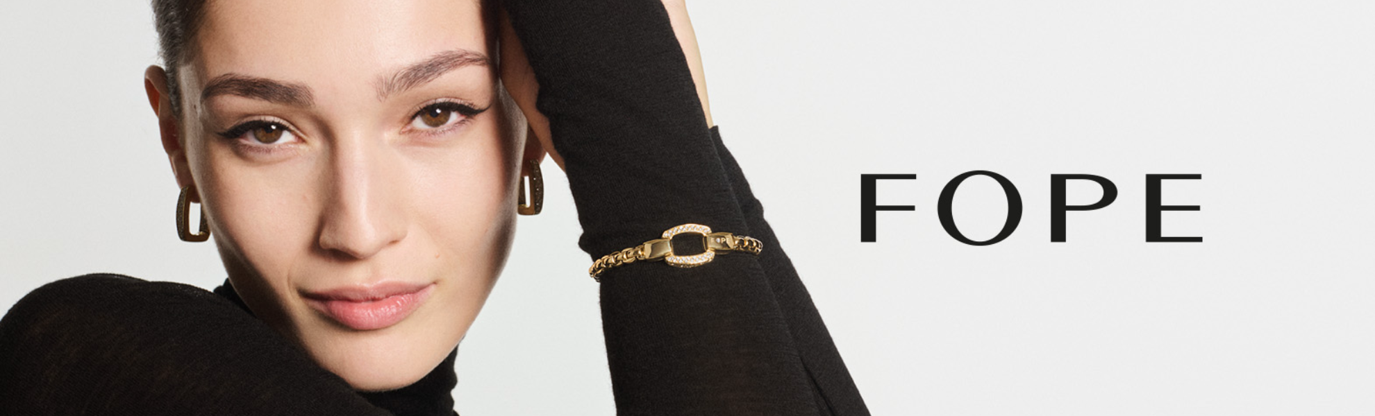 Woman wearing a gold bracelet with 'FOPE' branding on a white background