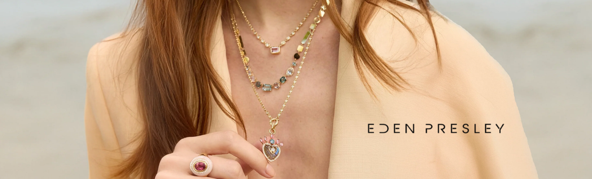 Person wearing layered necklaces with a blurred background, featuring the brand 'Eden Presley'.