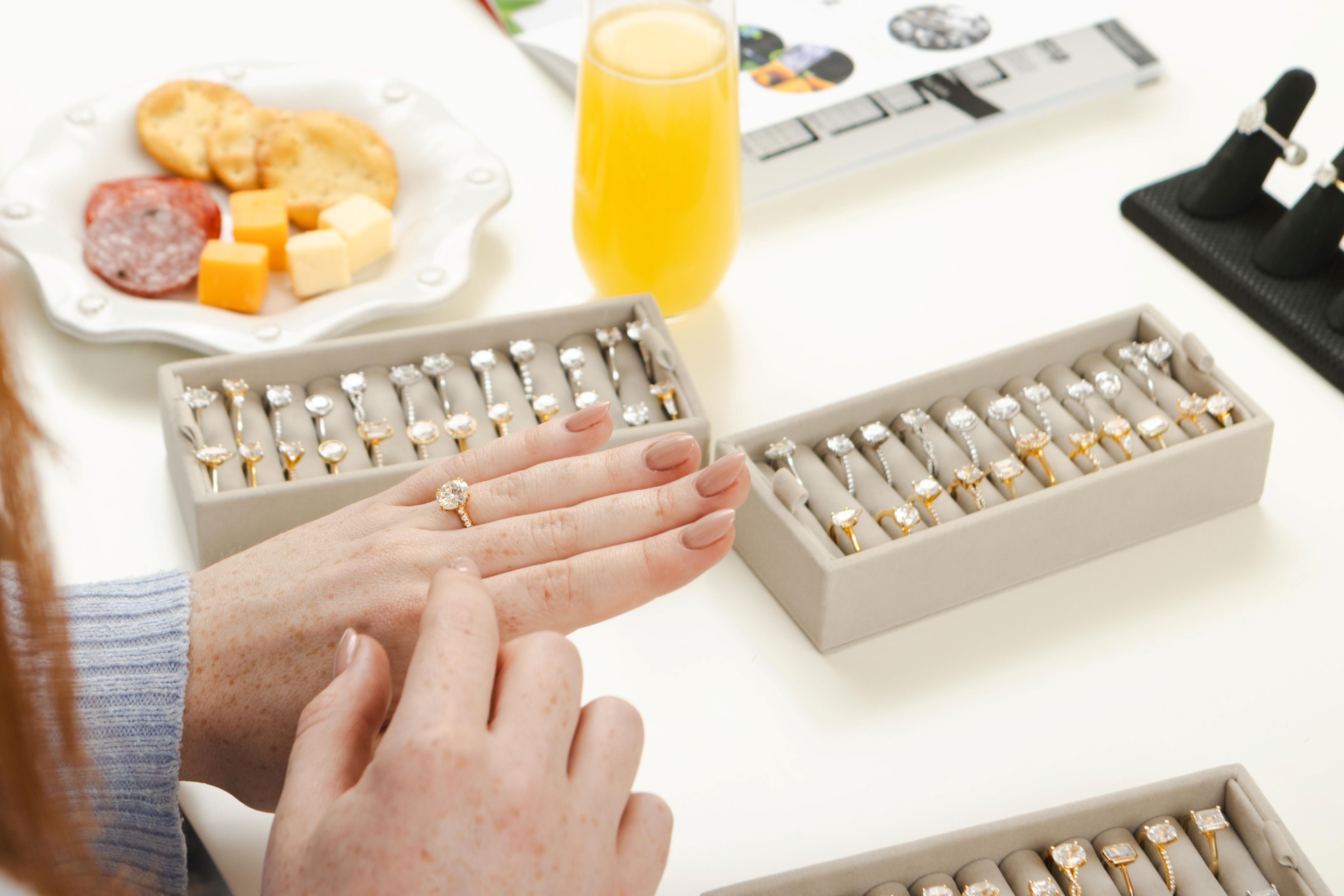 Person examining rings on a table with food and drinks in the background
