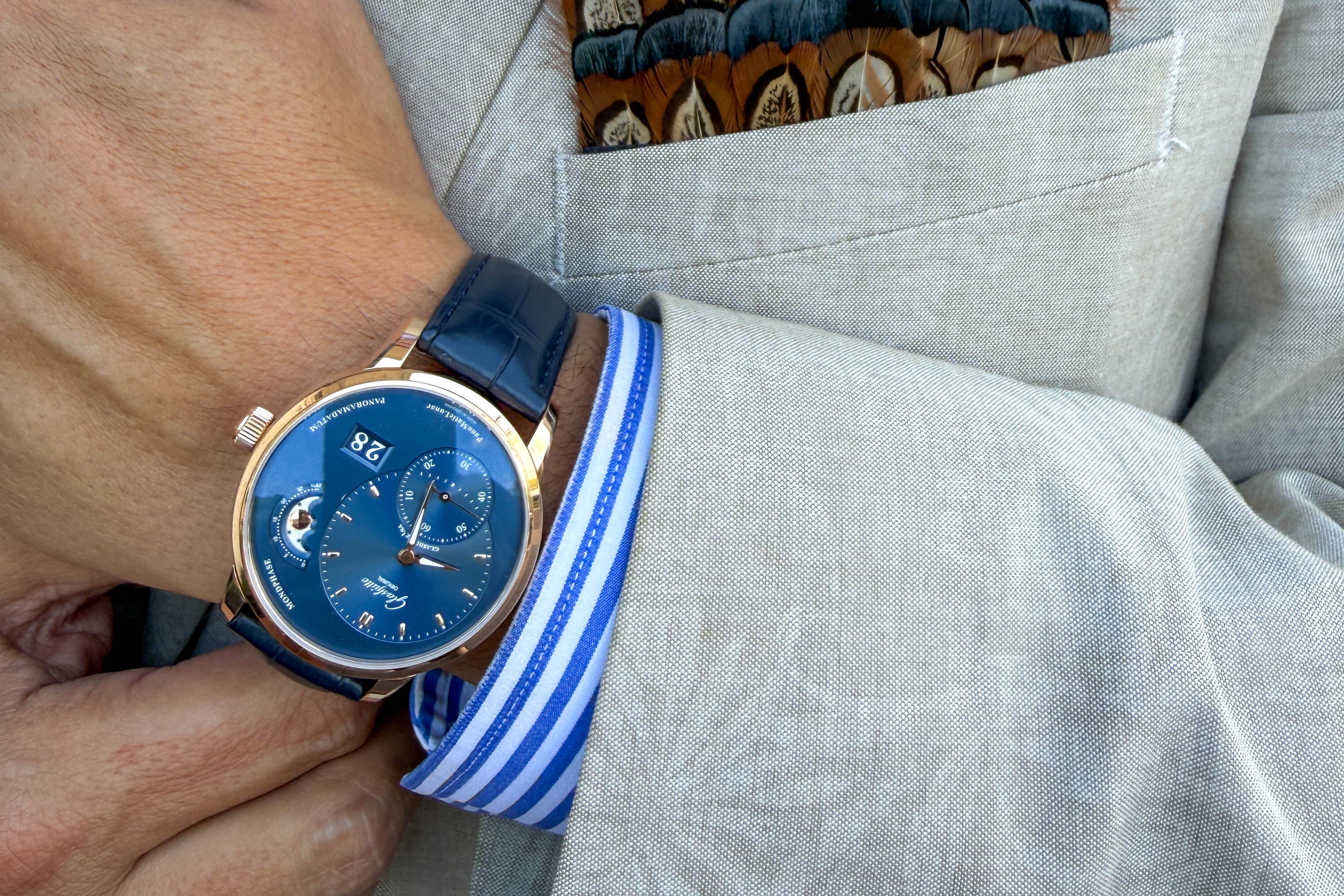 Person wearing a watch with a light gray suit and striped shirt