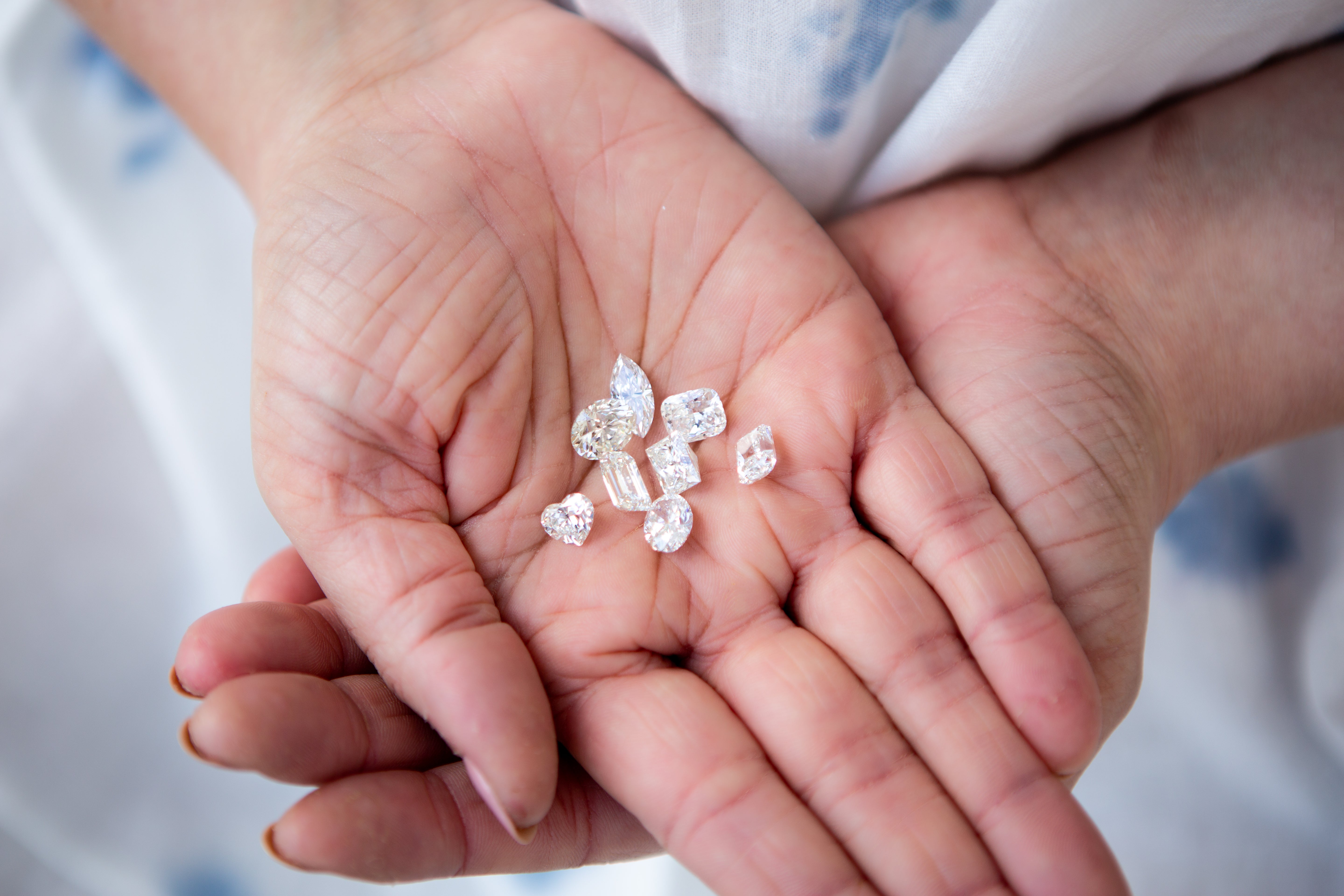 Hands holding small diamonds against a blurred background