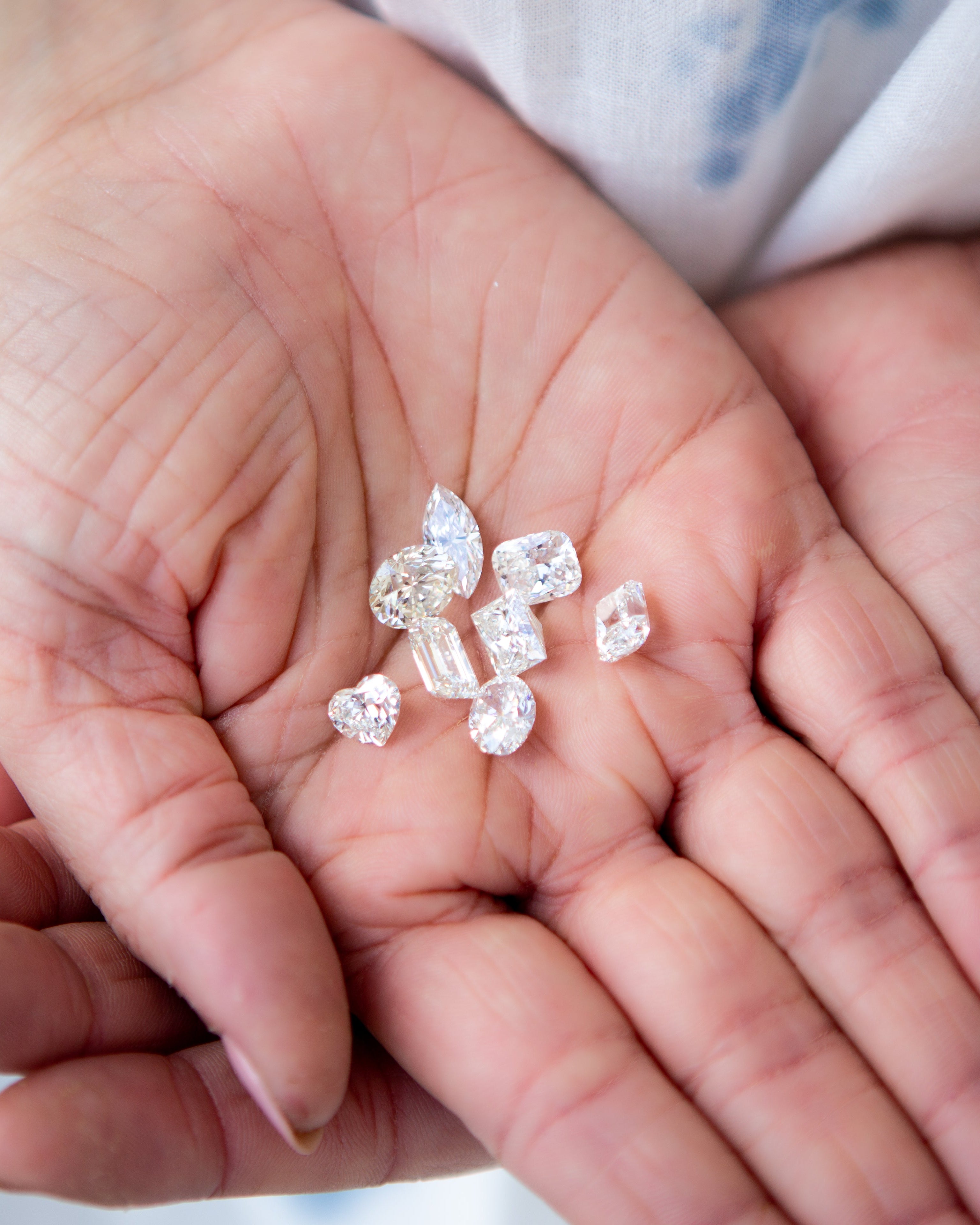 Hands holding small diamonds against a blurred background