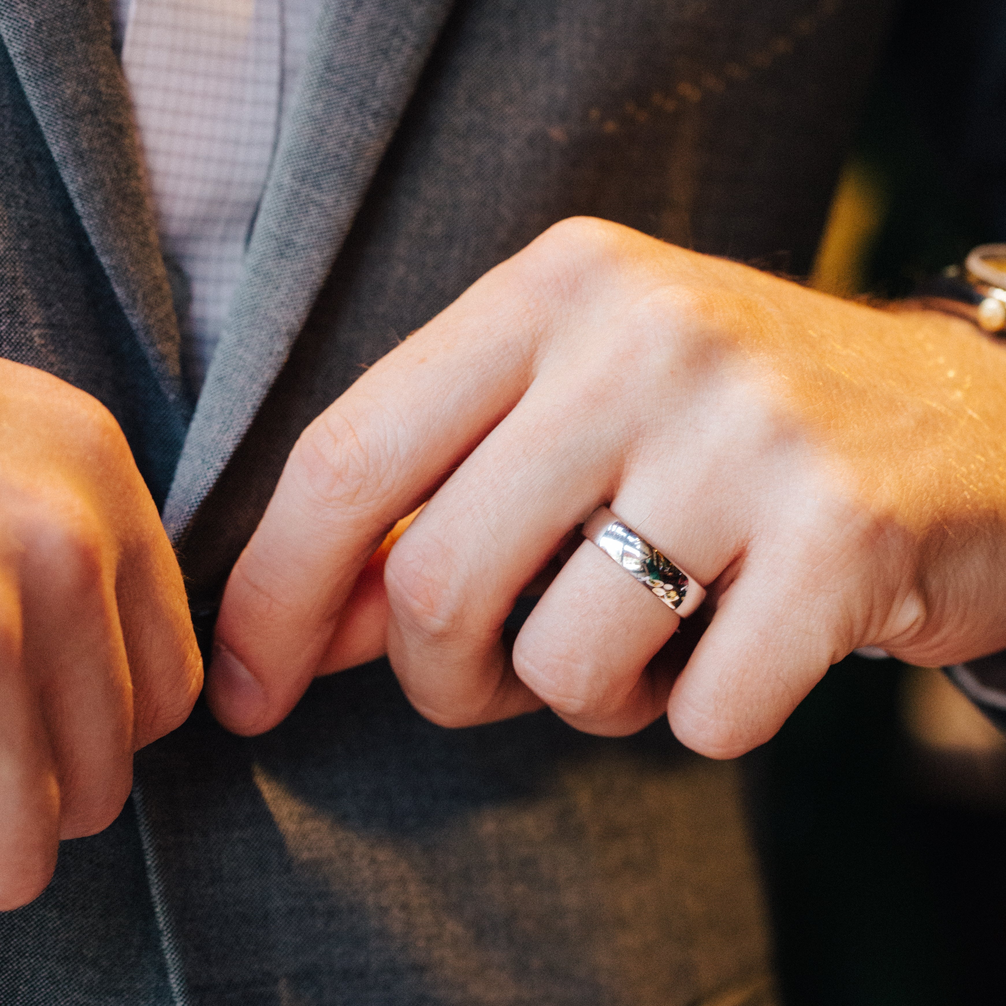 Close-up of a person's hand wearing a silver ring on a dark background