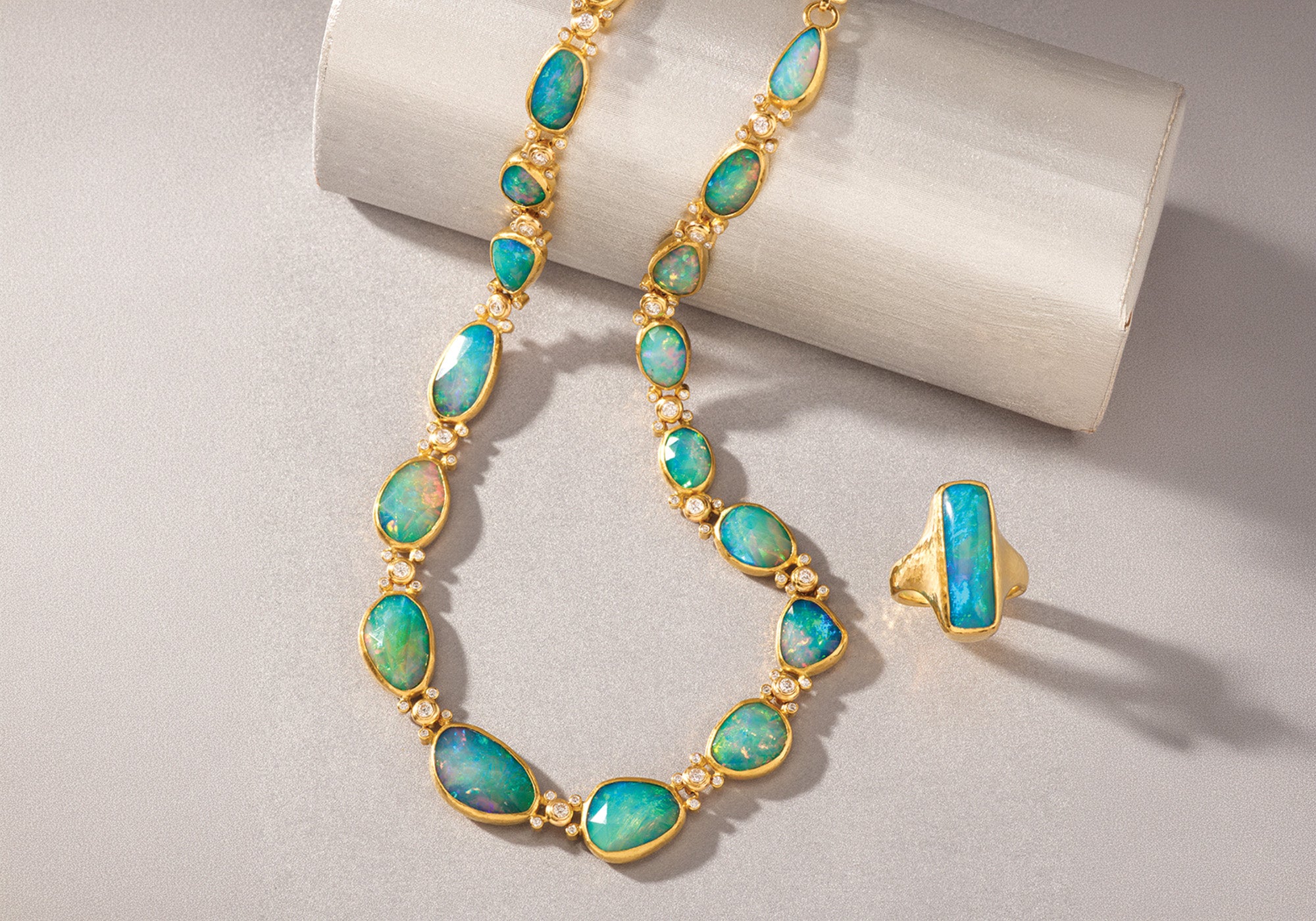 Opal necklace and ring set on a light gray background