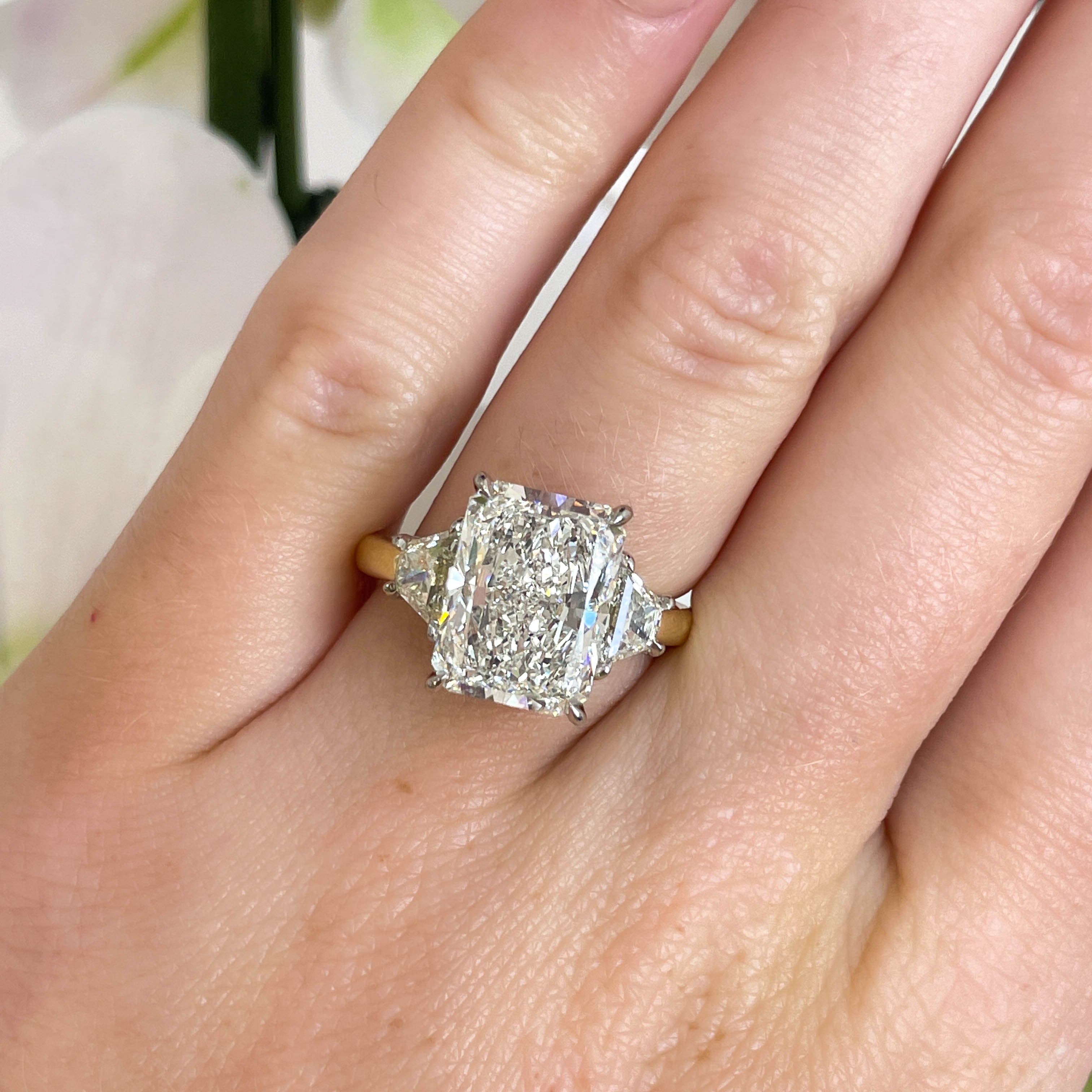 Diamond ring on a hand with a blurred floral background