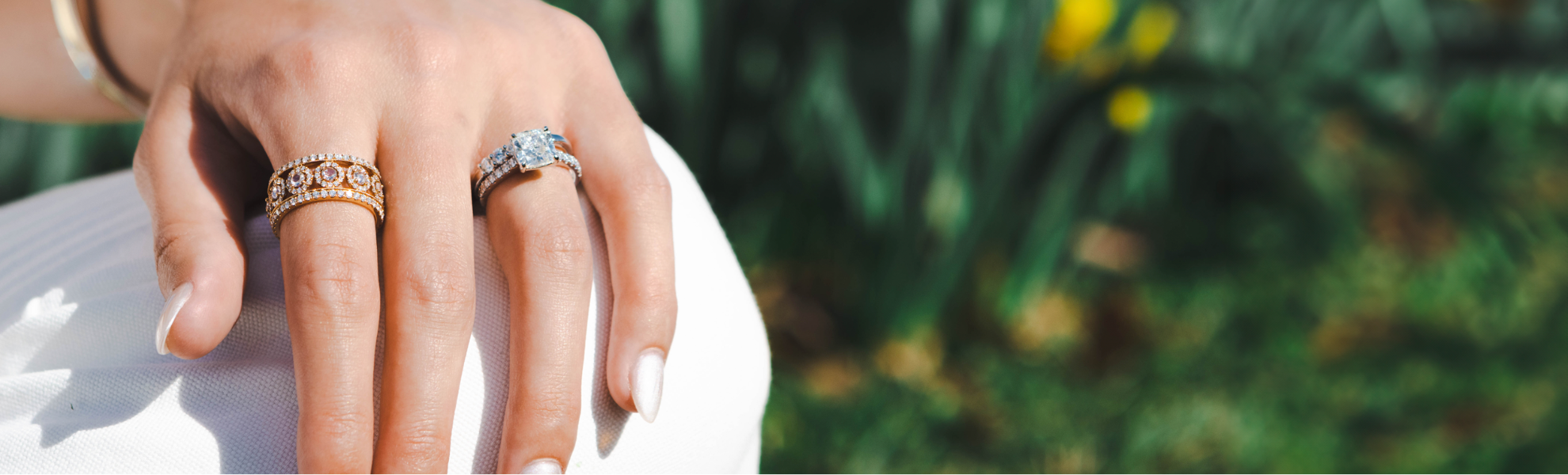 Close-up of a hand wearing two rings with a blurred natural background