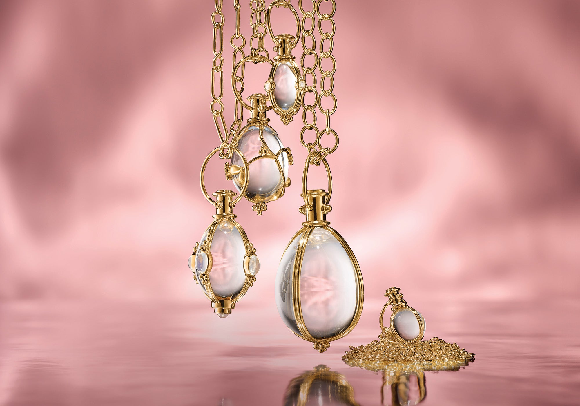 Gold necklaces with pink gemstones on a pink background