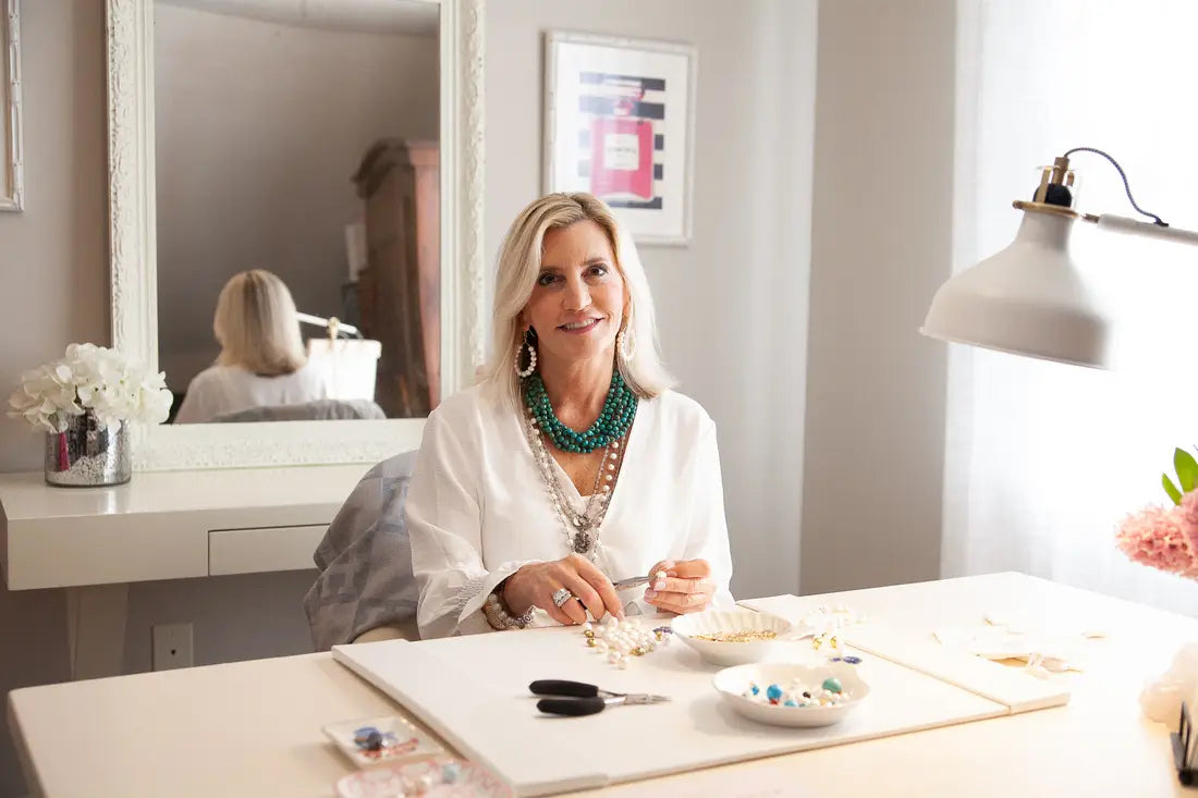 Woman sitting at a desk in a home office setting, surrounded by decor and furniture.